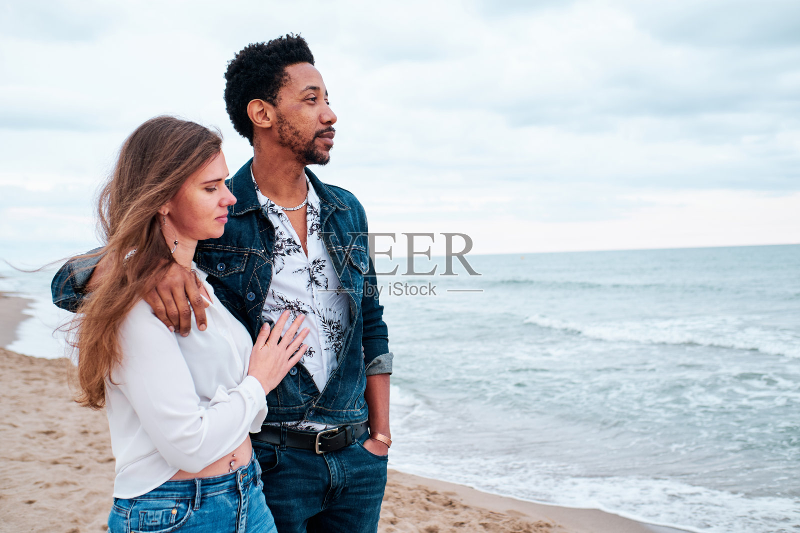 年轻的异族情侣在海滩上散步照片摄影图片