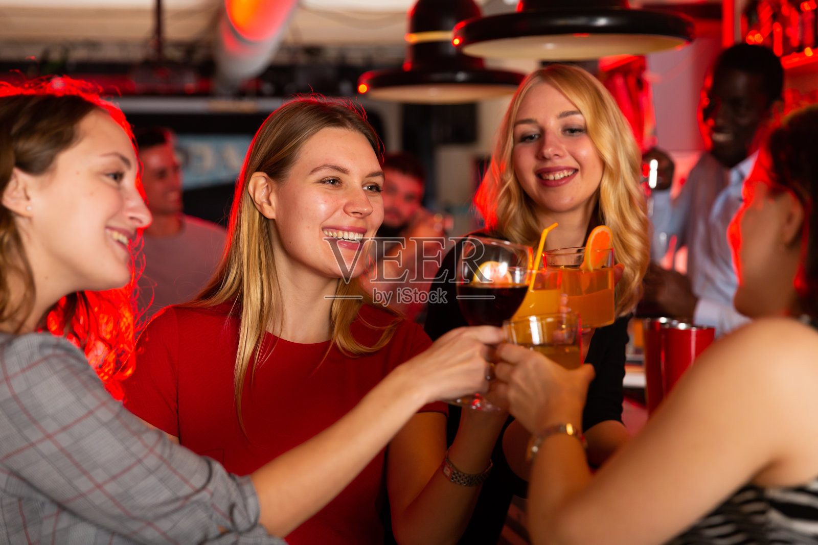 在夜总会里，朋友们捧着鸡尾酒谈笑风生照片摄影图片