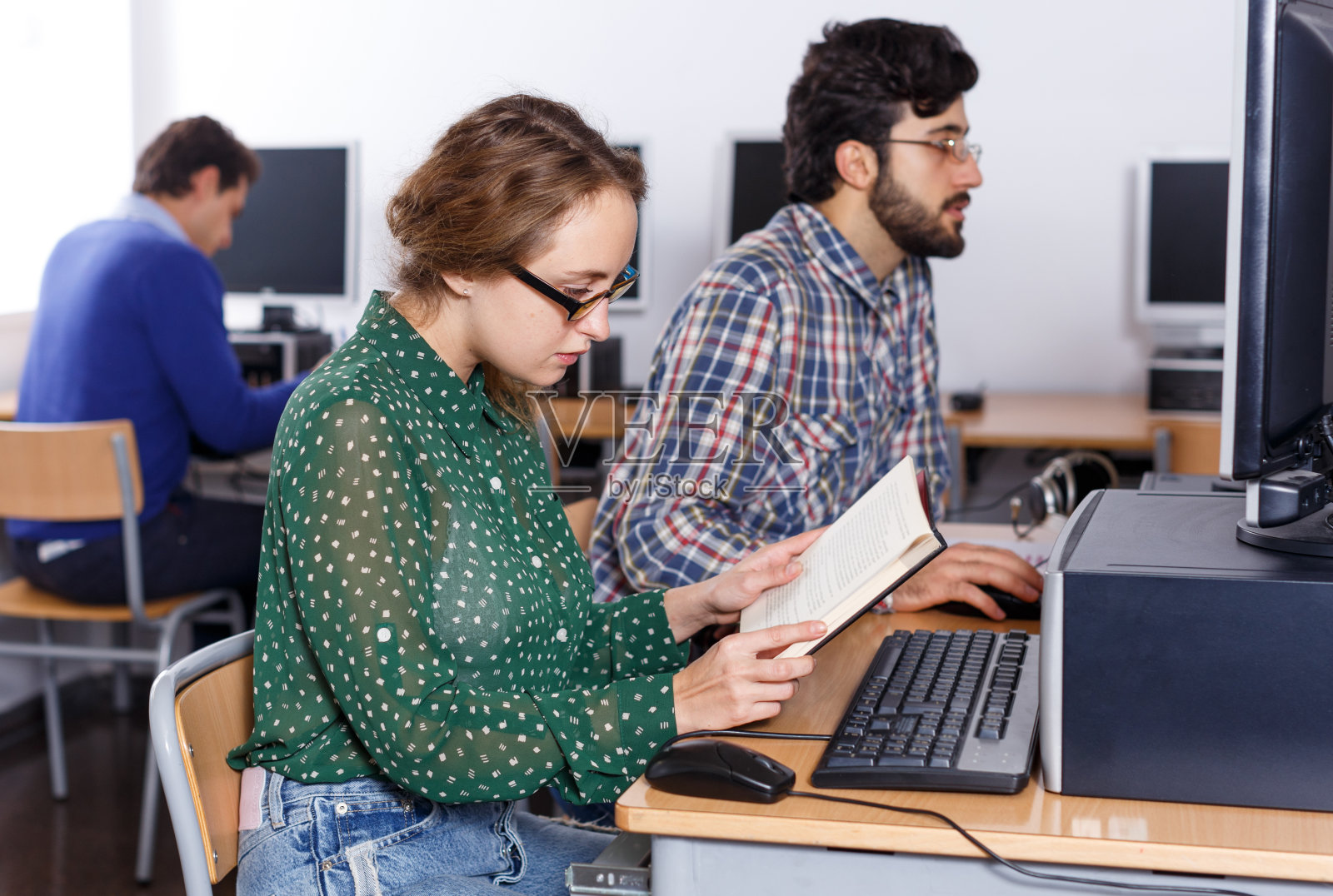 女学生在图书馆使用电脑和书籍照片摄影图片