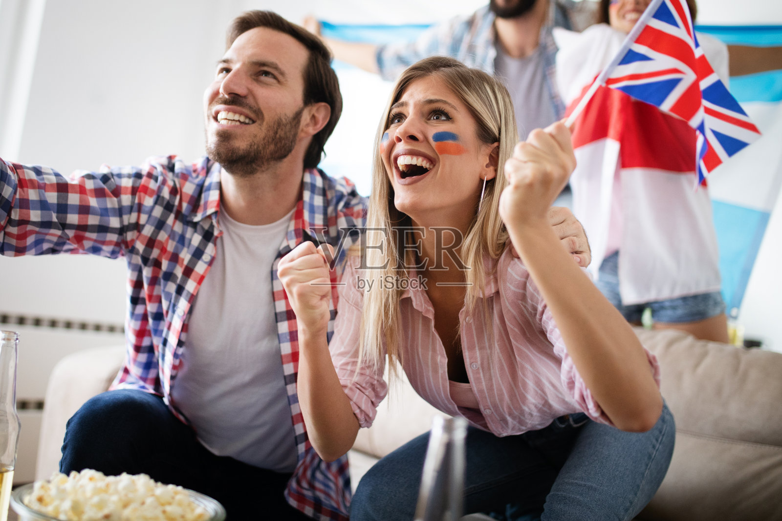 一对年轻的体育迷在家里看电视比赛照片摄影图片