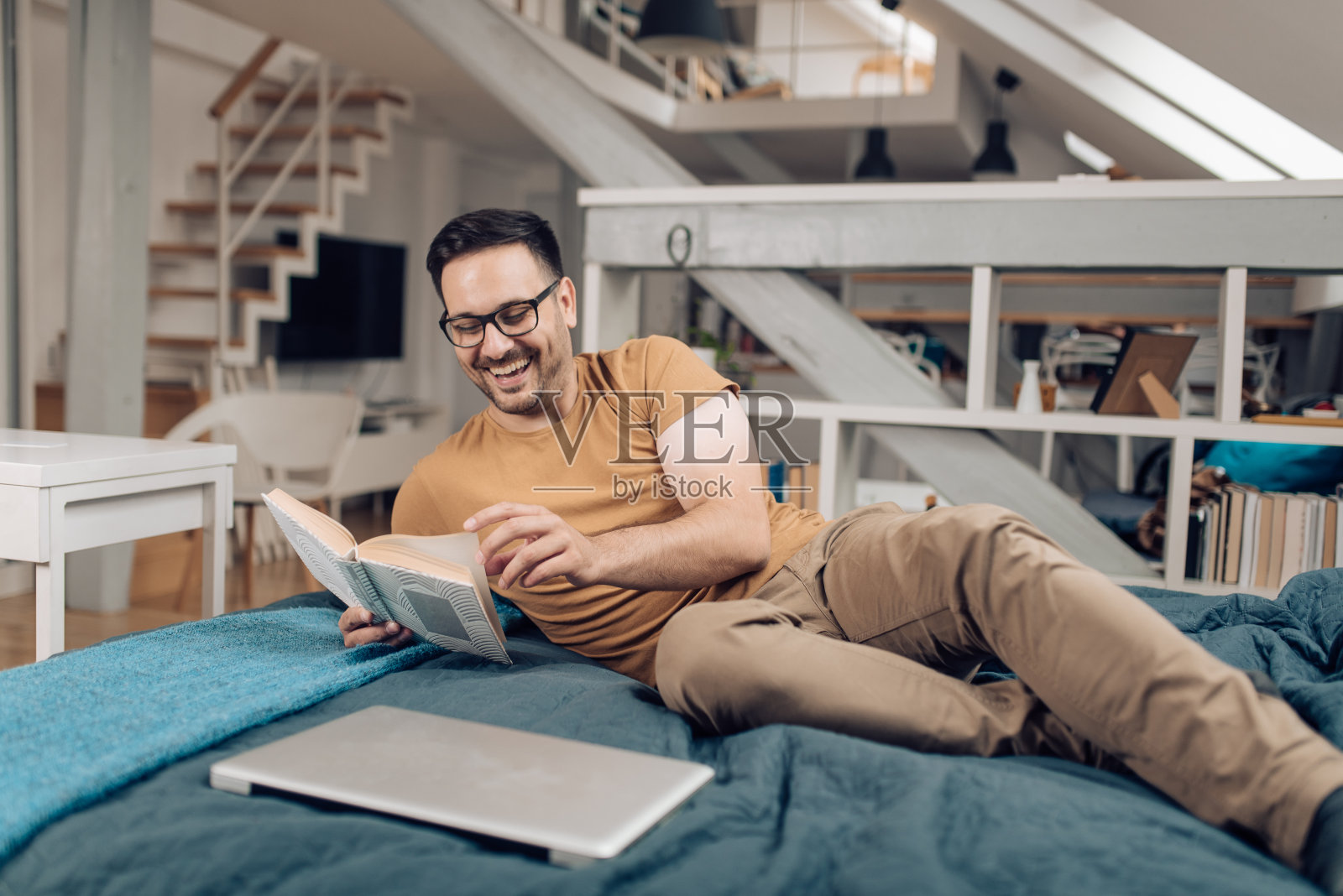 一个年轻人躺在床上看书照片摄影图片