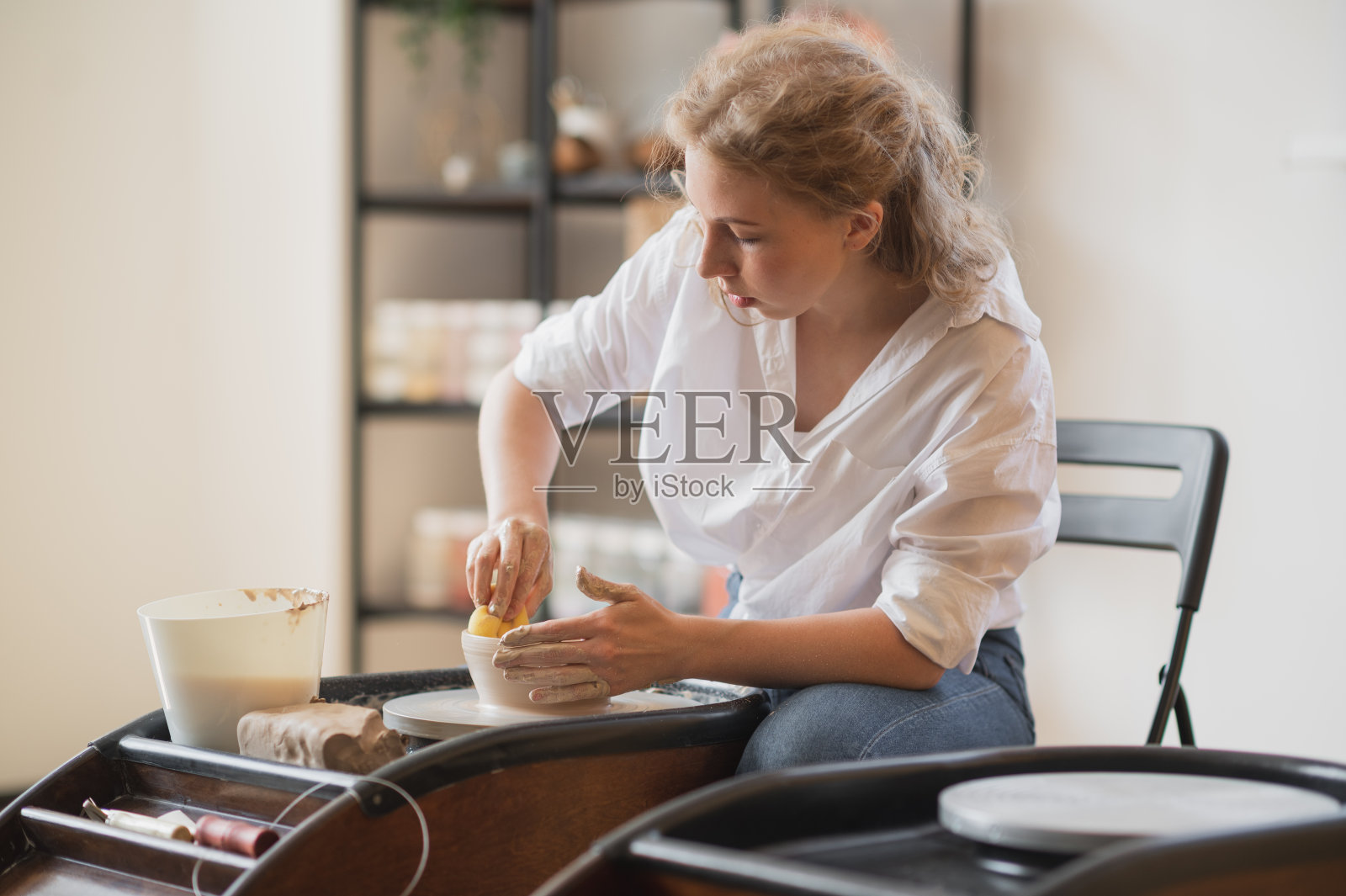 在陶工上工作的妇女用他们自己的双手轮子做盘子。特写照片的脏手塑造粘土照片摄影图片