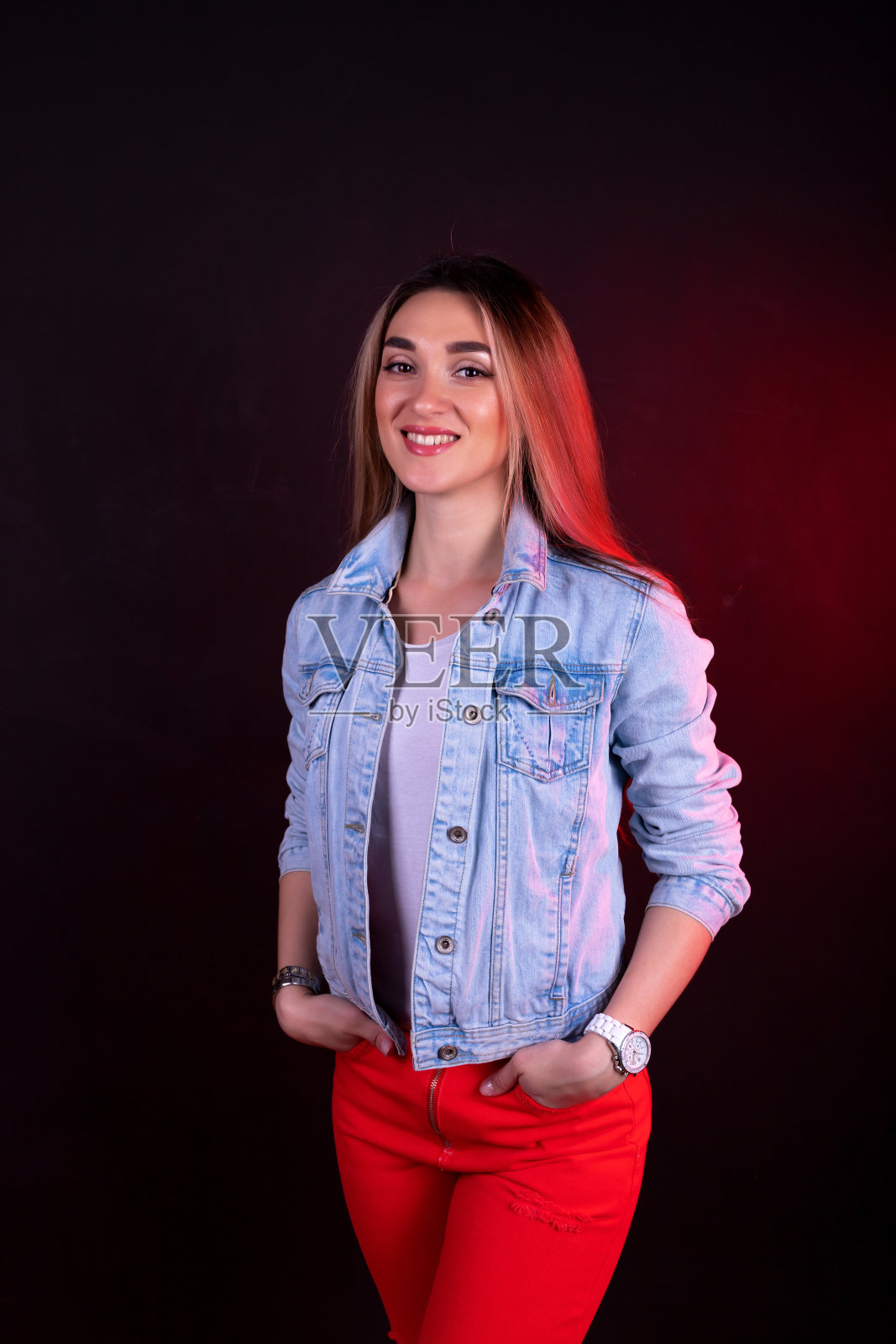一个穿着牛仔夹克和红裤子，面带微笑的年轻女孩照片摄影图片