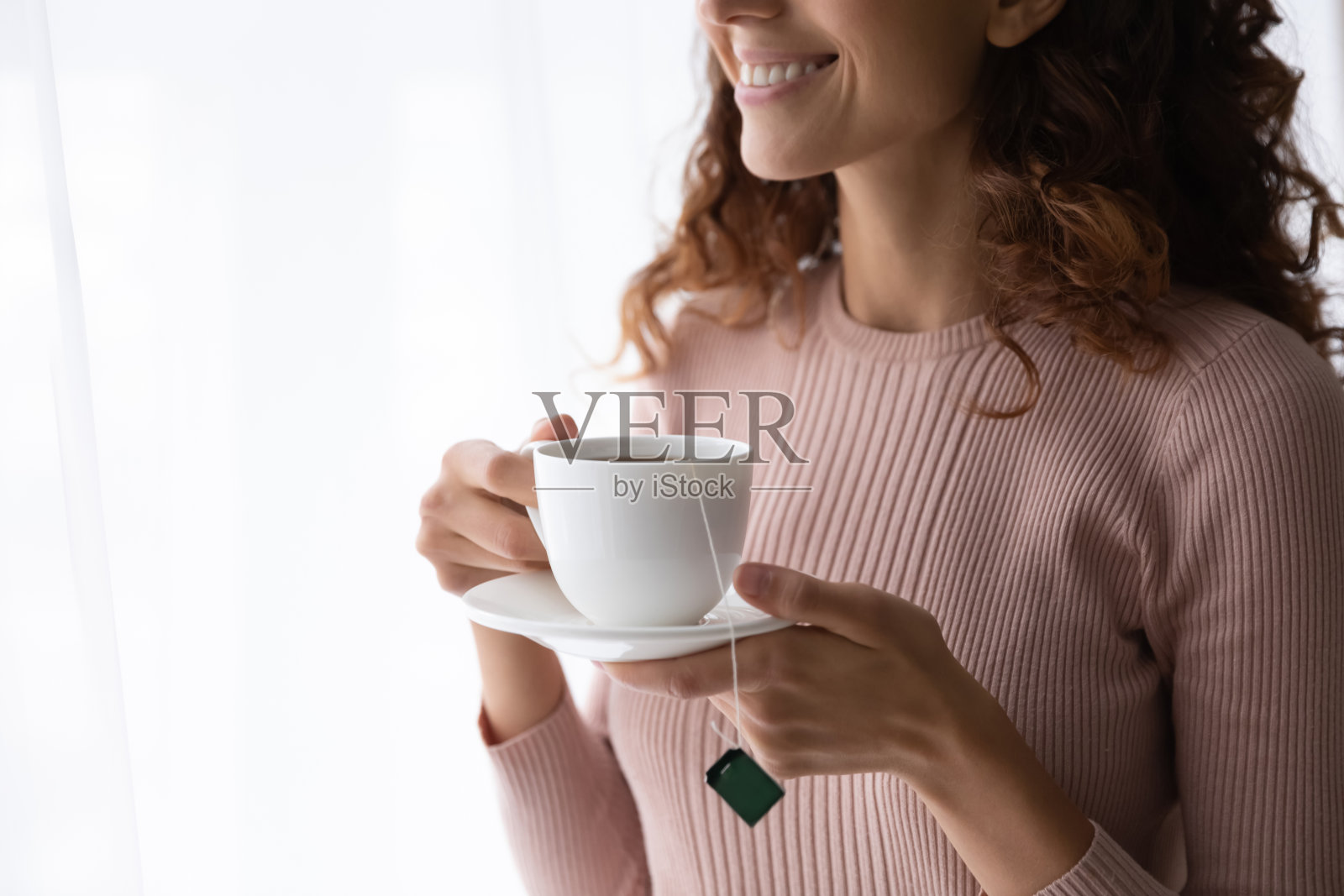 近距离的微笑美丽的女人拿着白色的茶杯照片摄影图片