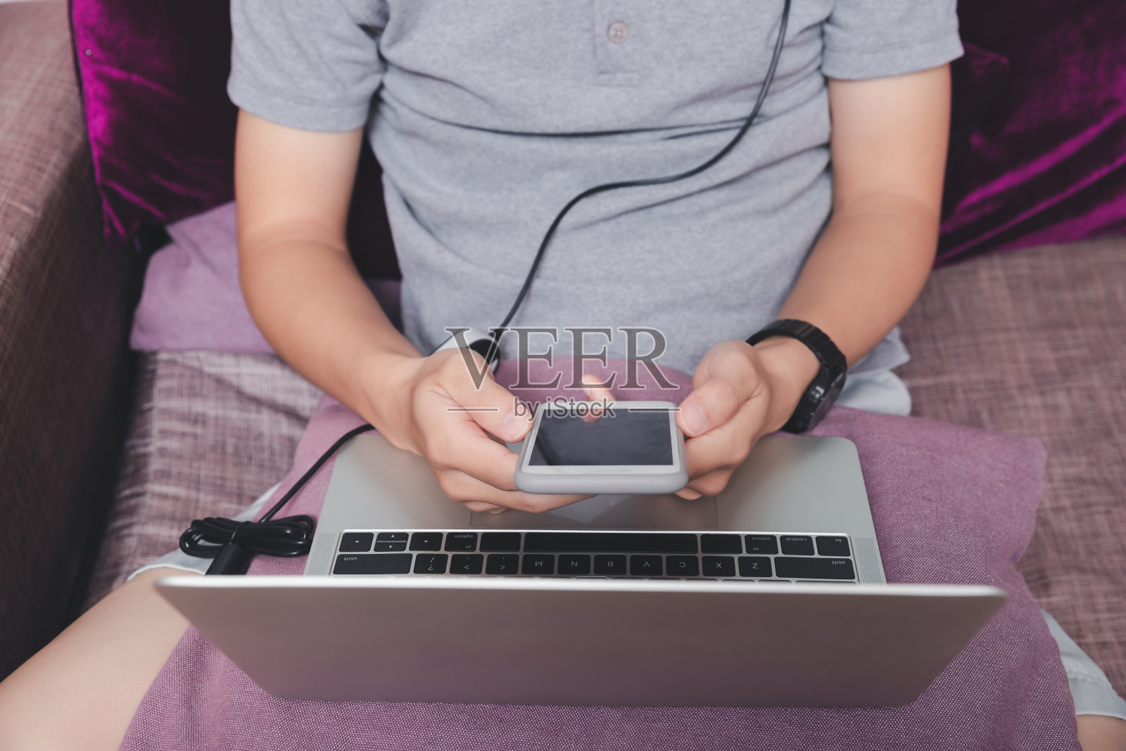 一个拿着智能手机的男人站在家庭办公室的一角。照片摄影图片