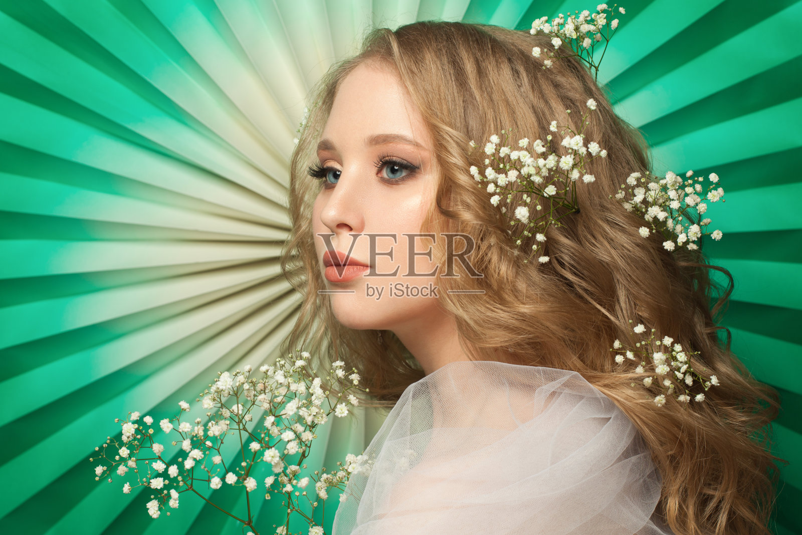 年轻的模特，头发上插着鲜花，背景是绿色的照片摄影图片