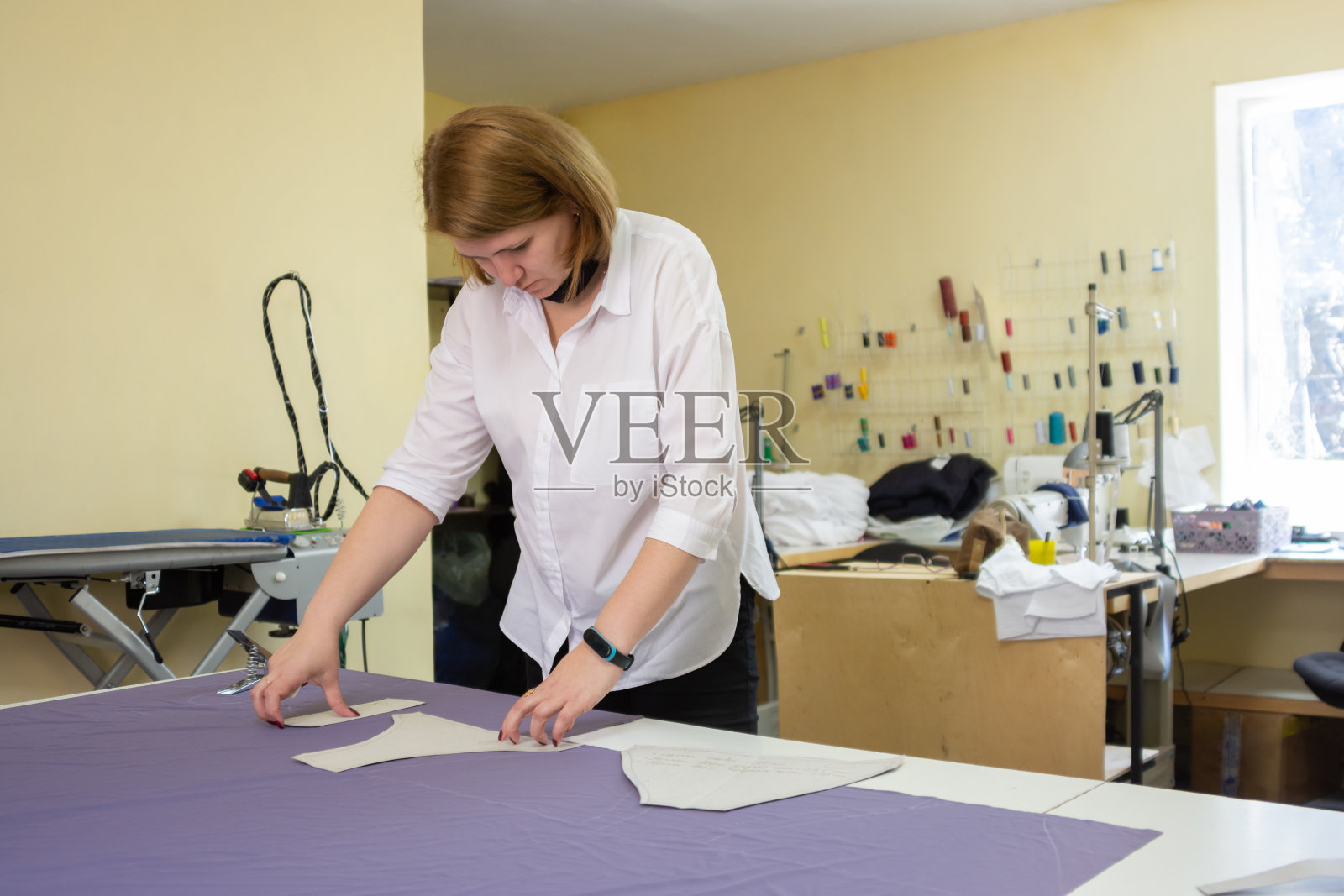 刀具在车间的一张大桌子上把图案摆在布料上照片摄影图片