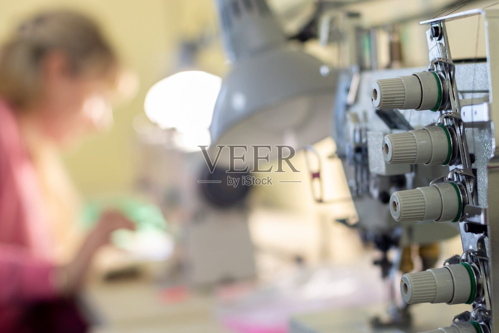 缝纫设备的特写与线和一个工人在背景照片摄影图片