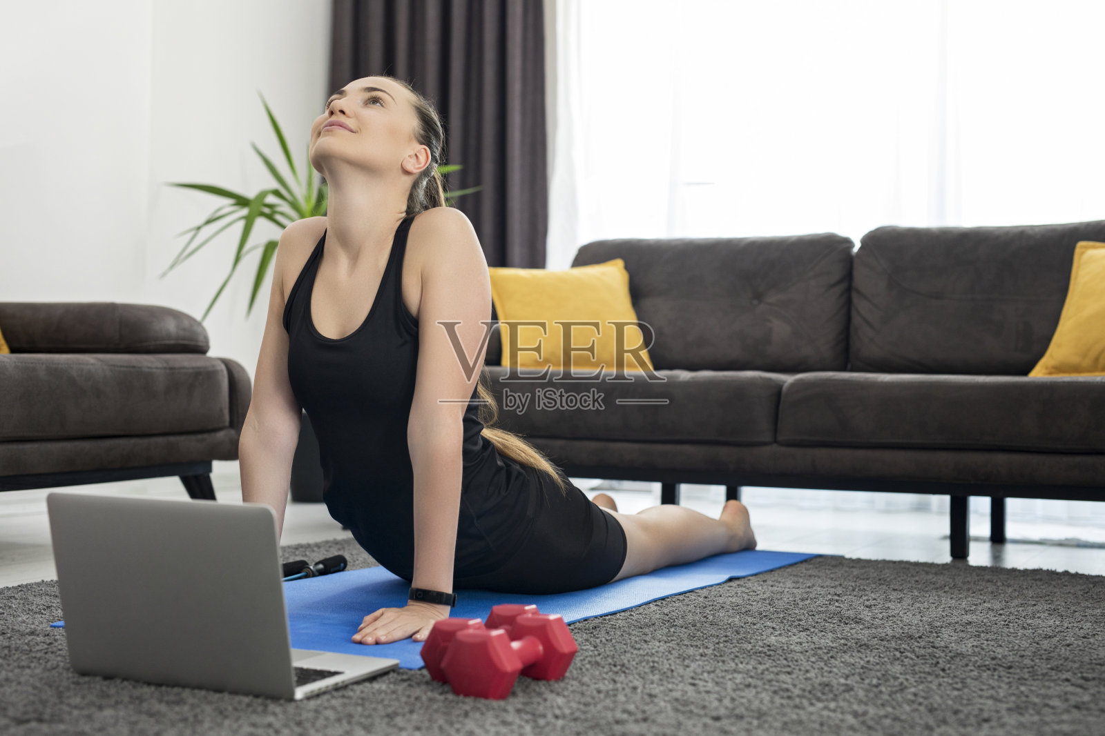 年轻女子在家里用笔记本练瑜伽照片摄影图片
