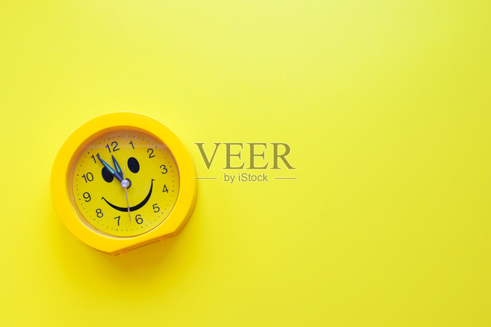 黄色背景上的黄色塑料微笑钟。照片摄影图片