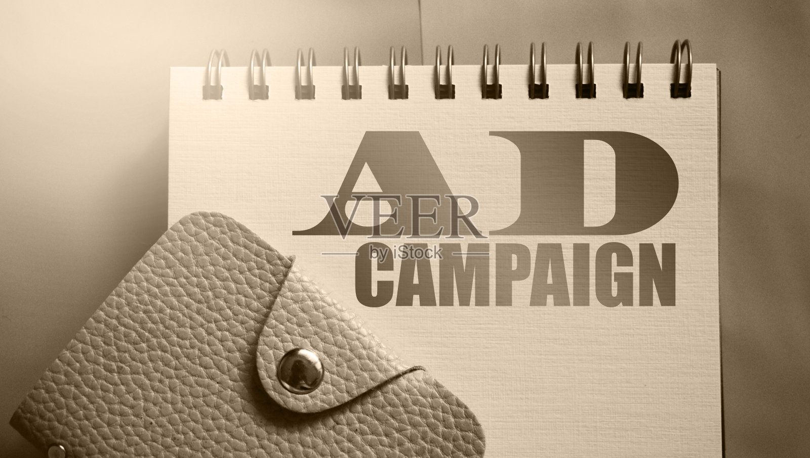 广告词在抄写页和皮革钱包。暖灰色调和选择性焦点。广告营销经营理念照片摄影图片