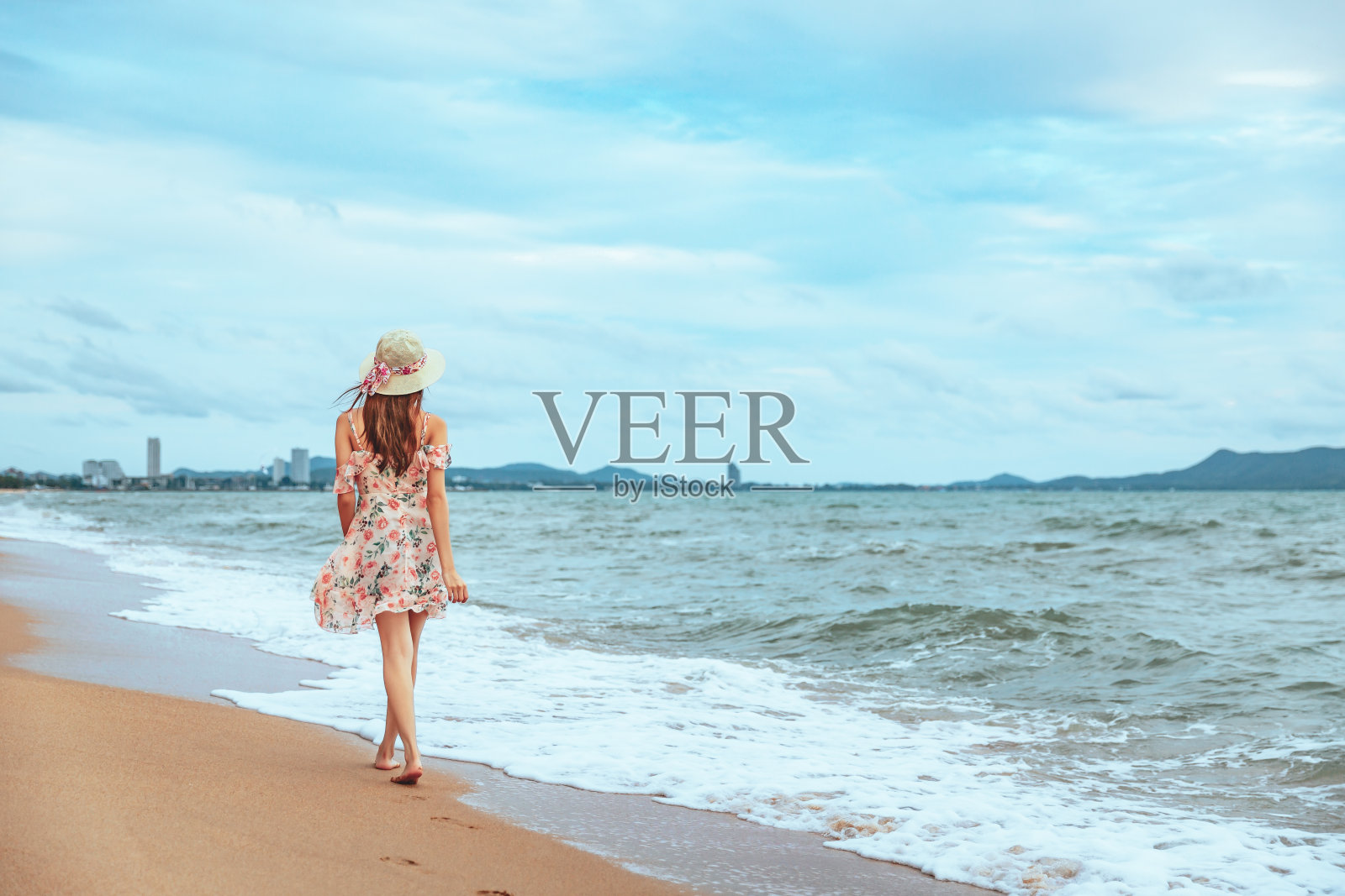 在海滩上散步的女旅行者照片摄影图片