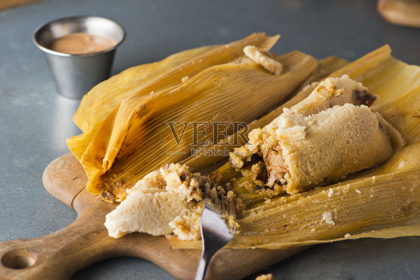 玉米粉蒸肉、猪肉和鸡肉调味后卷进马萨饼，再用香蕉叶蒸熟。经典的墨西哥风味或德墨风味。配以墨西哥辣酱，鳄梨酱，米饭和豆子。照片摄影图片