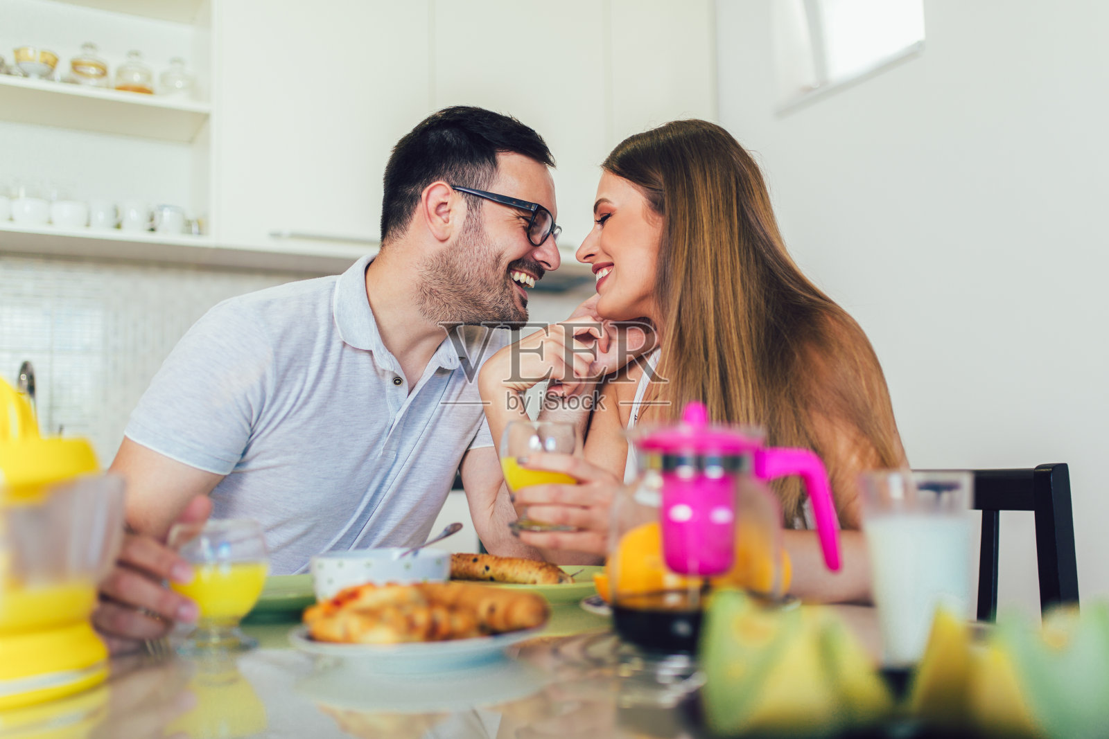 年轻幸福的夫妇坐在现代化的公寓里，一起吃早餐。照片摄影图片