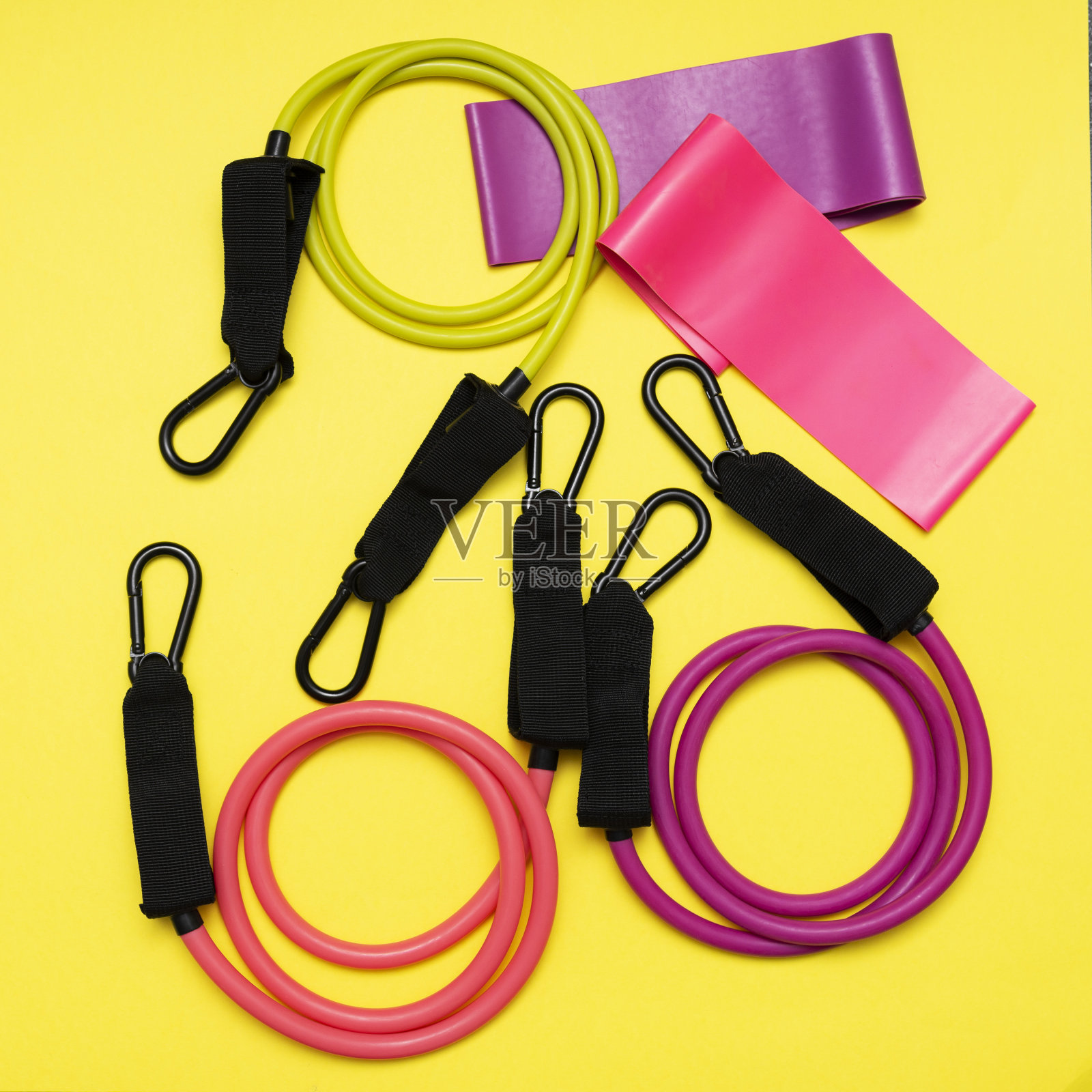 在黄色背景上适合不同负荷程度的膨胀器和松紧带。用于健身的橡皮筋。体育运动器材照片摄影图片