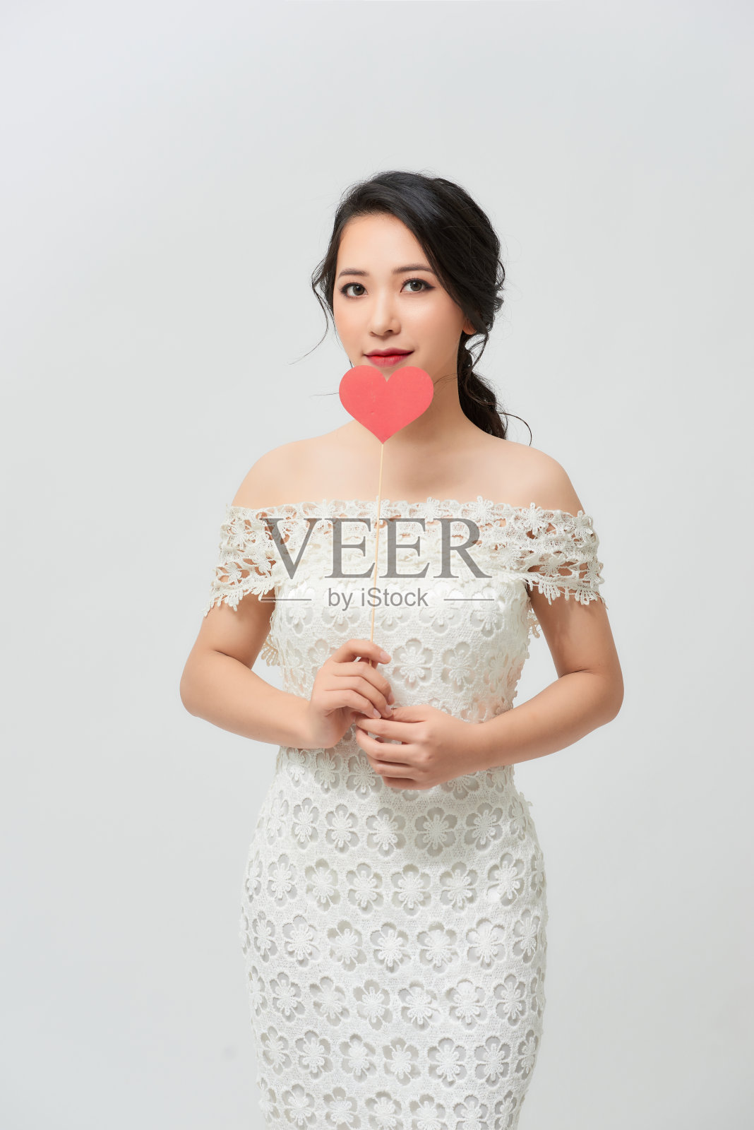 优雅的亚洲女人在白色的裙子拿着红色的心与微笑棒照片摄影图片