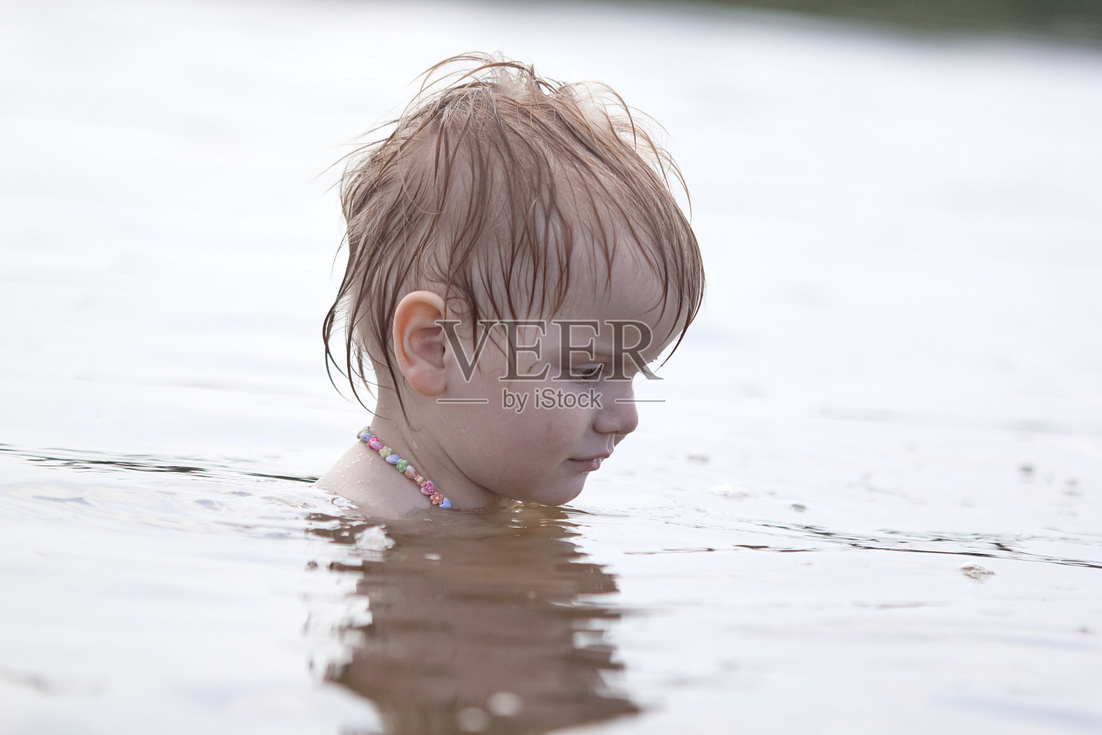 独立的小女孩坐在湖上的水里照片摄影图片