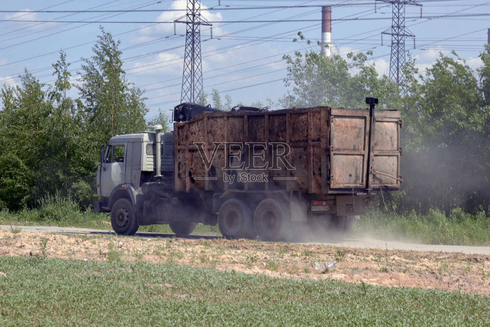 一辆旧垃圾车在尘土中沿着道路行驶照片摄影图片