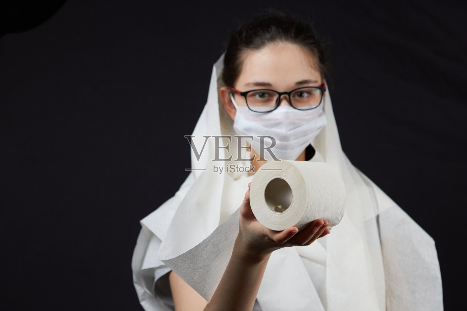 一个贪婪的年轻人，戴着眼镜和面具，裹在卫生纸里照片摄影图片