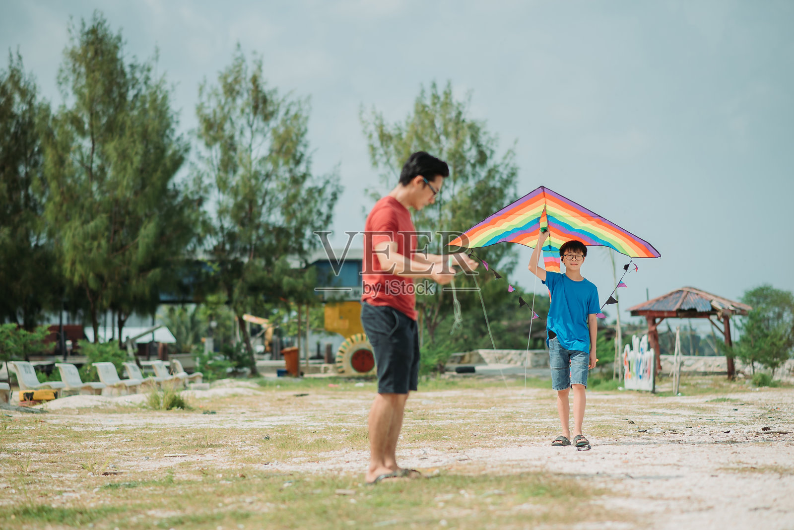 亚洲华人儿子抱着和学习如何在海边放风筝照片摄影图片