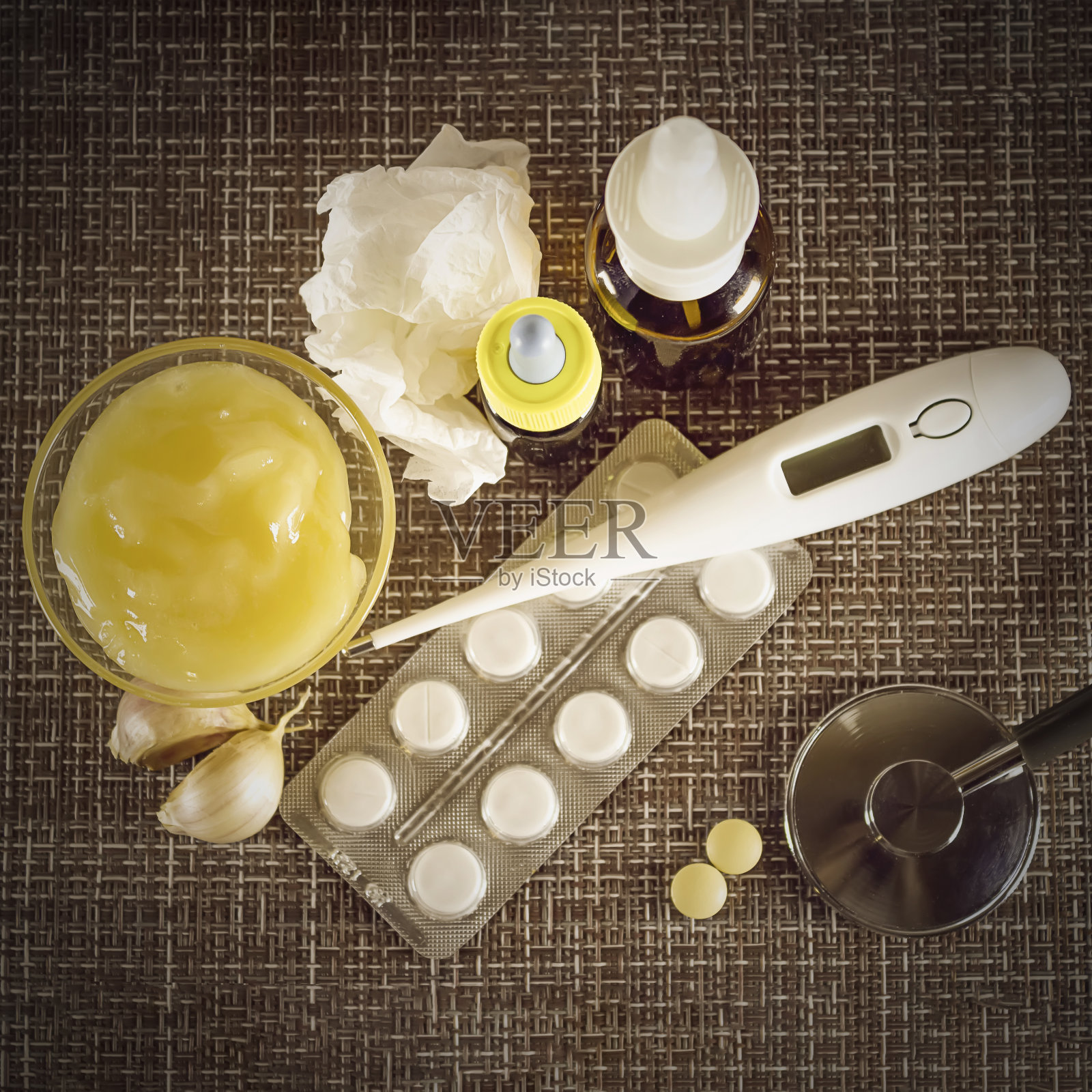 治疗感冒和流感。各种药物，感冒药，喉喷雾剂，滴鼻剂，还有一张放在棕色背景上的纸巾。治疗流感。医学平。照片摄影图片