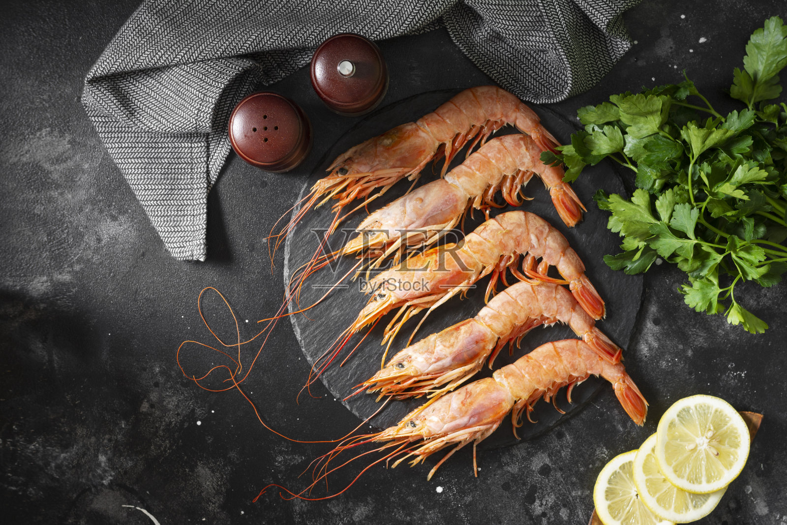 黑色餐桌上的黑盘子里放着大螯虾。海鲜是健康的饮食照片摄影图片