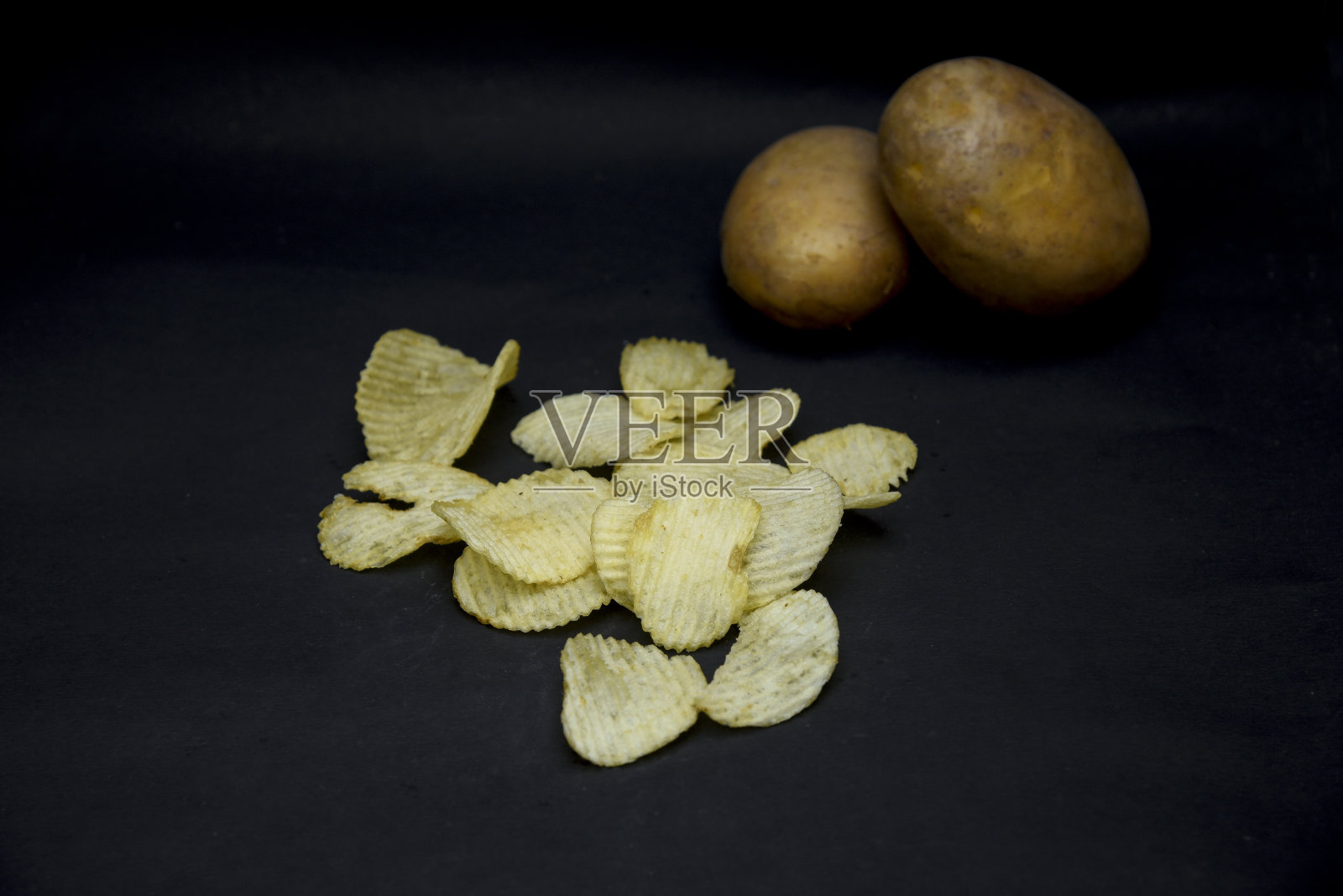 黑桌子上碗里的脆薯片照片摄影图片