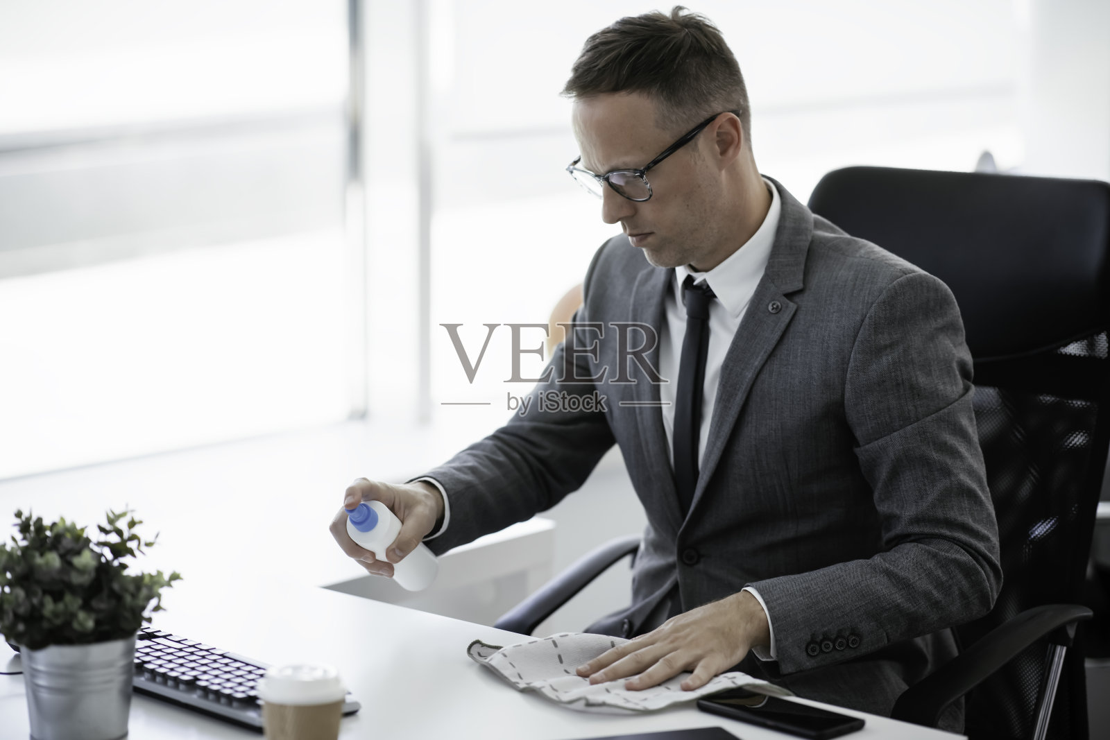 商人正在为办公室的桌子消毒。照片摄影图片