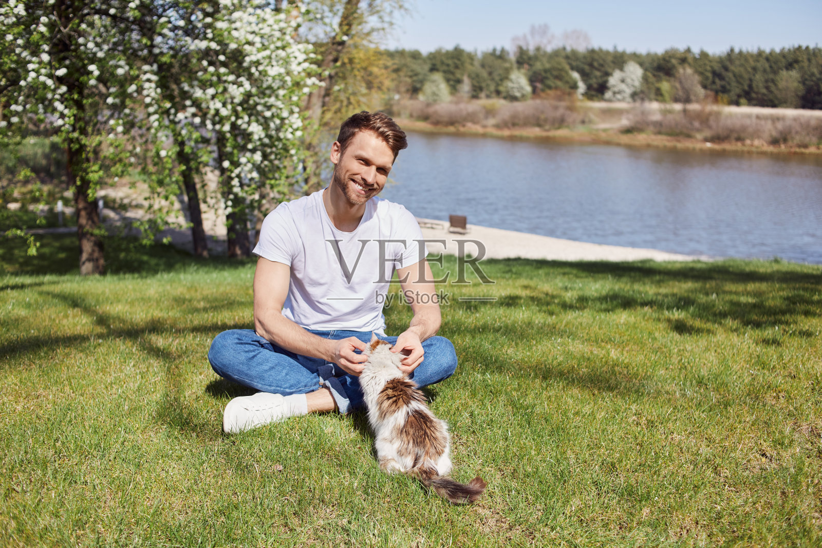 可爱的年轻男子爱抚他顽皮的猫照片摄影图片