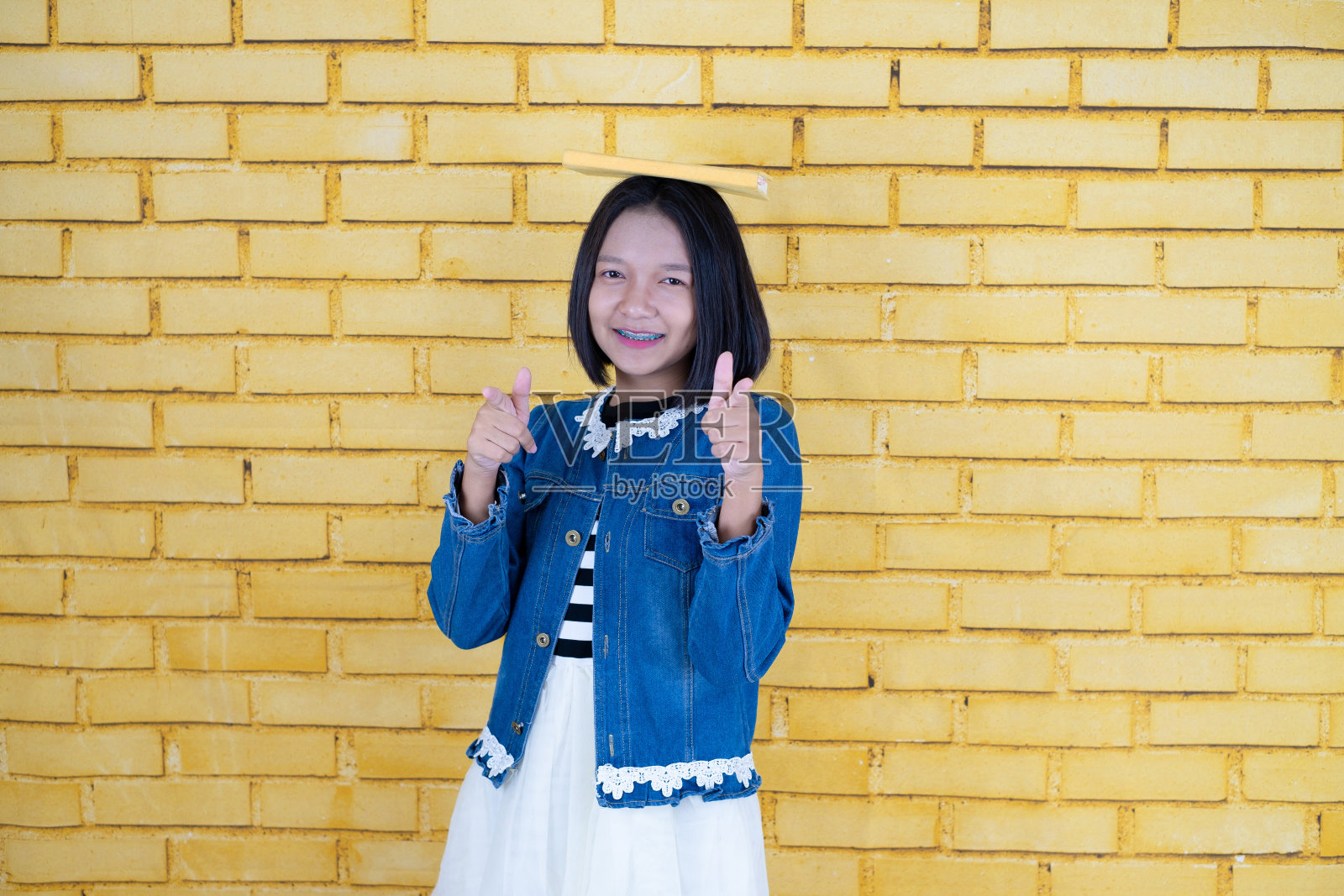 肖像亚洲年轻女孩拿着黄色背景的黄色书。照片摄影图片