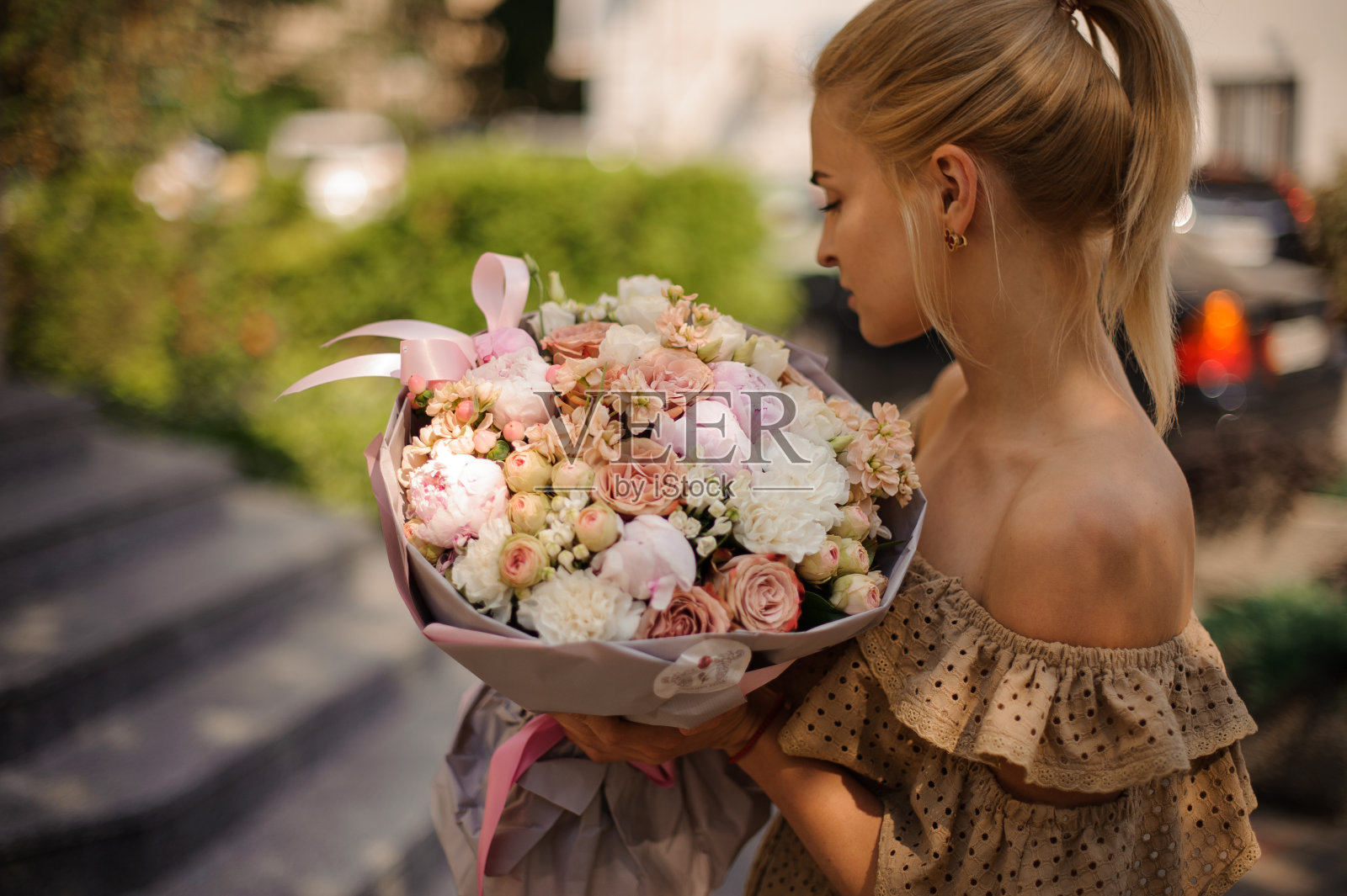 金发女人拿着漂亮精致的花束，看着它照片摄影图片