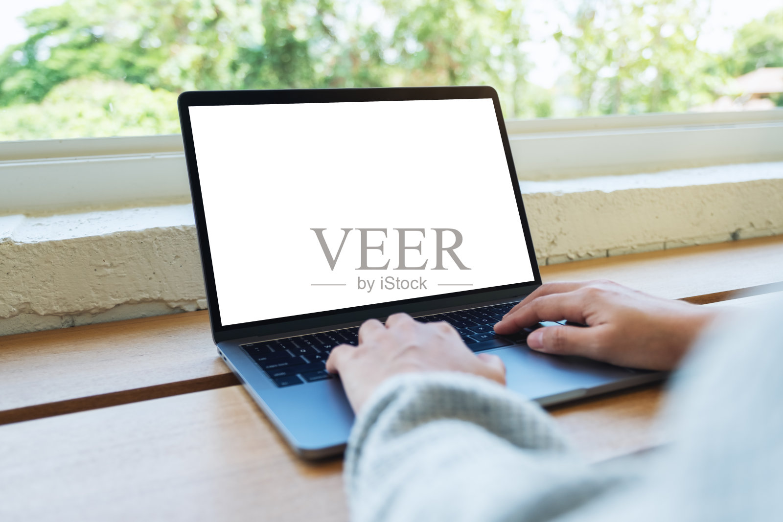 一个女人在木桌上用着笔记本电脑的键盘打字照片摄影图片