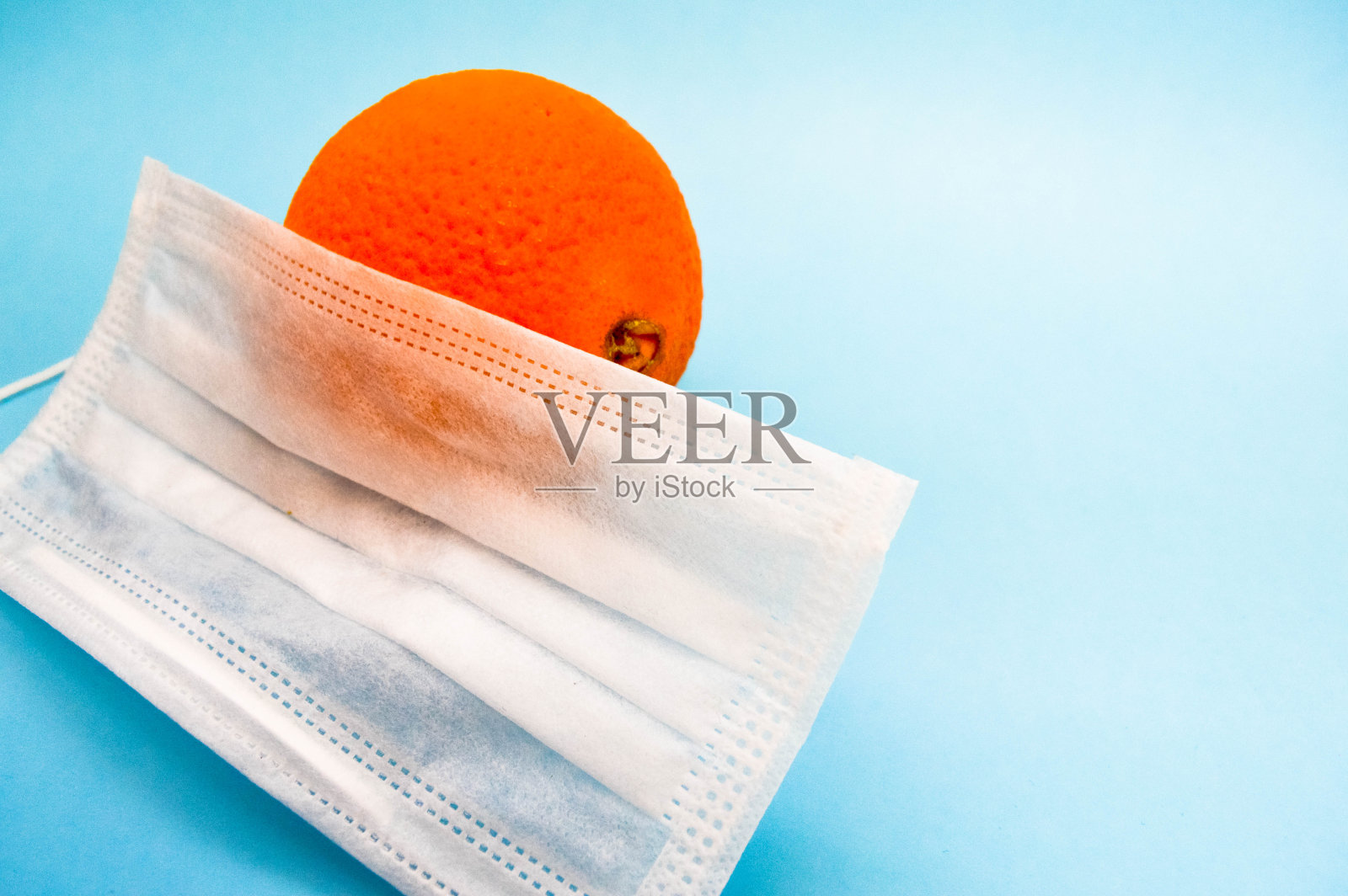 橘汁戴一次性口罩，保护皮肤免受冠状病毒和病毒感染。预防在海湾季节。维生素C和面膜可以保护身体照片摄影图片