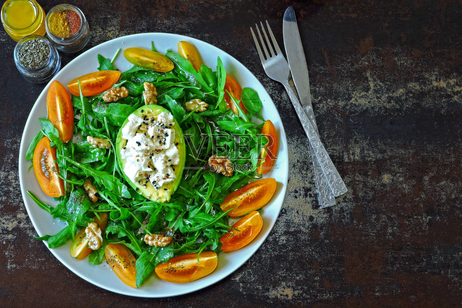 含有芝麻菜、鳄梨、黄色番茄和白奶酪的健康沙拉。照片摄影图片