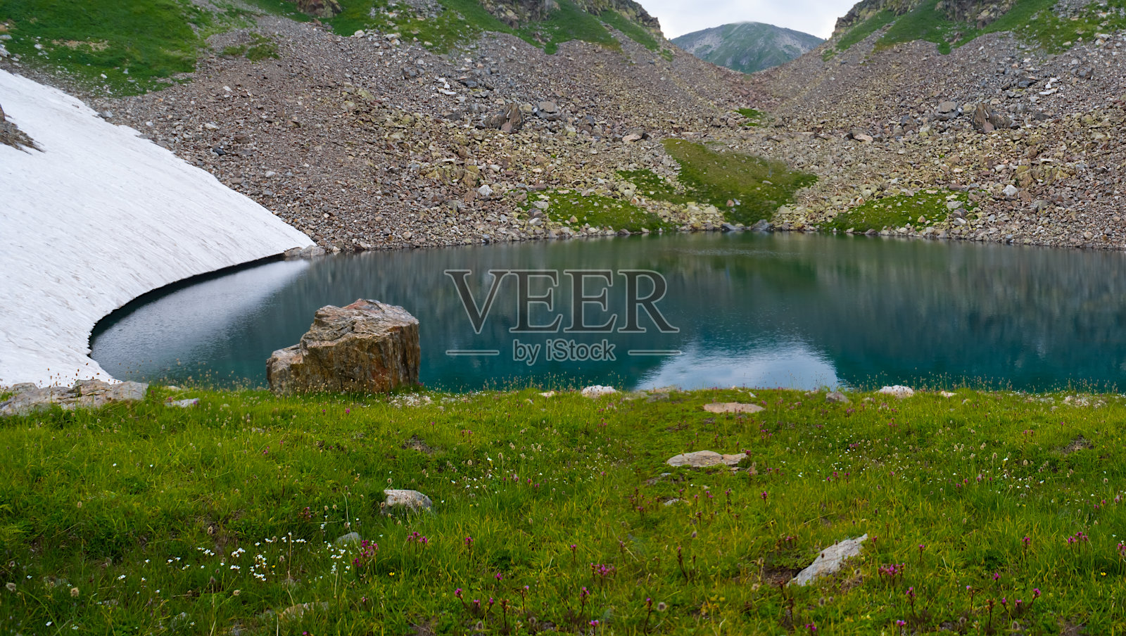 小湖位于山谷碗中，水雪草户外为背景照片摄影图片