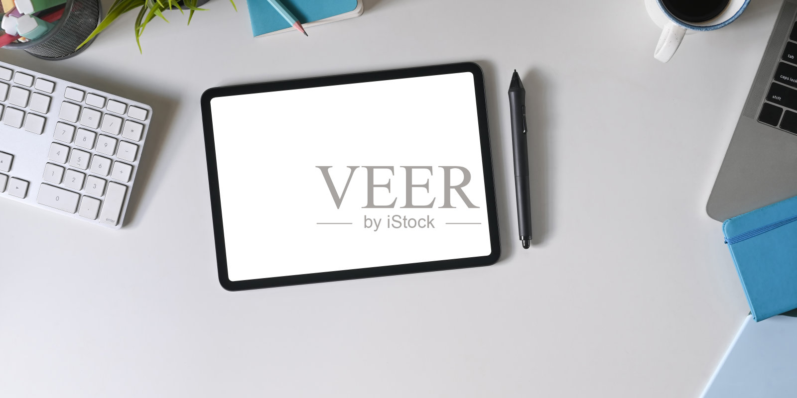 俯视图的工作空间周围是白色屏幕平板电脑和办公设备。照片摄影图片