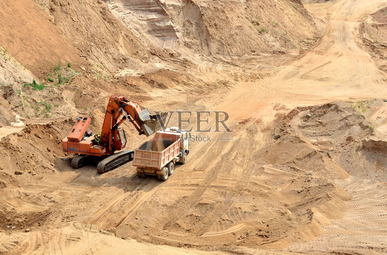 在采石场，挖掘机把沙子装进重型自卸卡车照片摄影图片