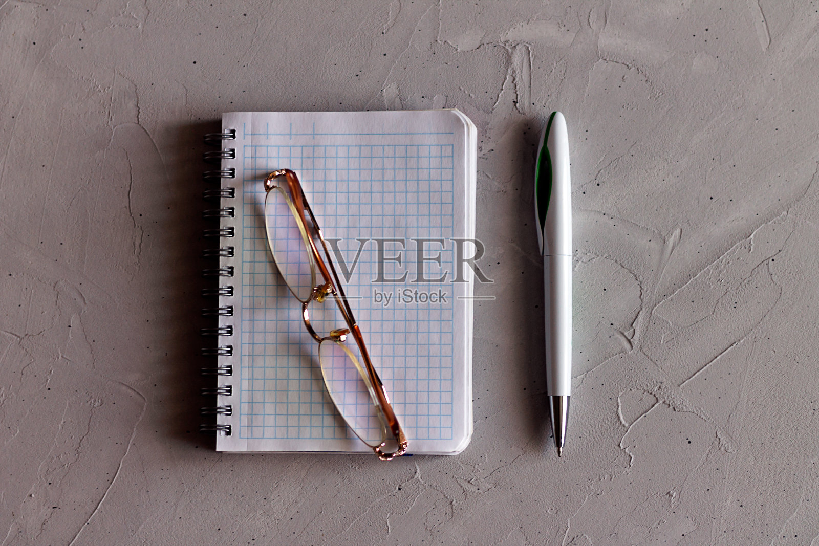 笔记本，眼镜和笔在灰色的表面上照片摄影图片
