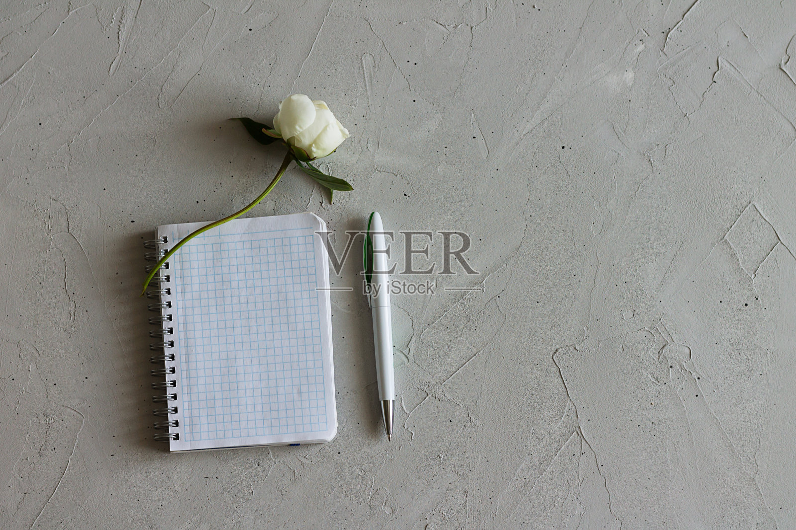 笔记本，花和笔在灰色的表面上照片摄影图片