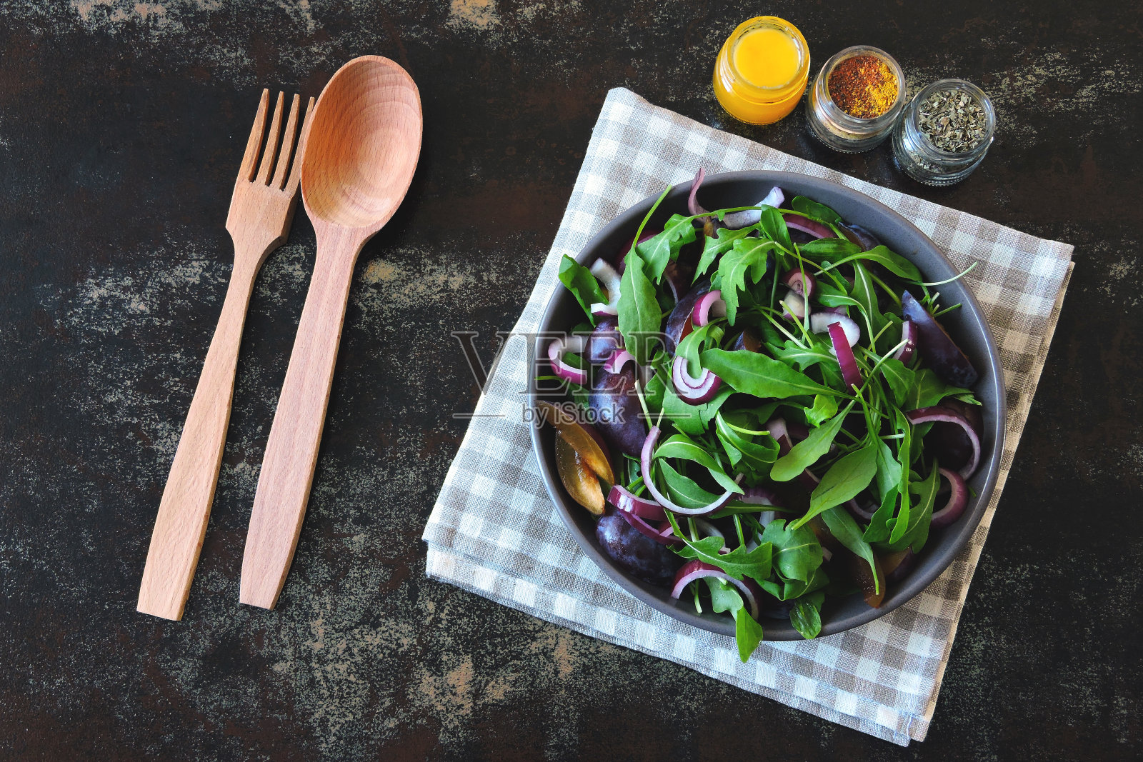 健康的沙拉，芝麻菜，李子和蓝色的洋葱在一个碗在时尚破旧的背景。照片摄影图片