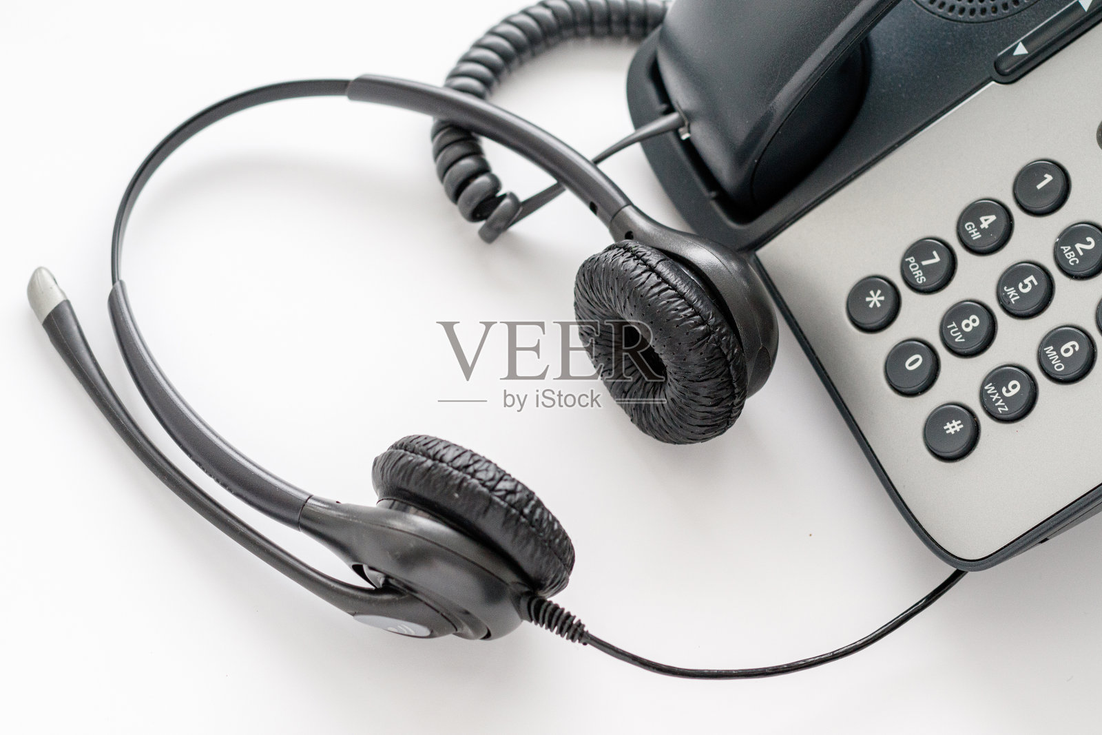 一个耳机躺在一个旧的按键式电话旁的特写照片摄影图片