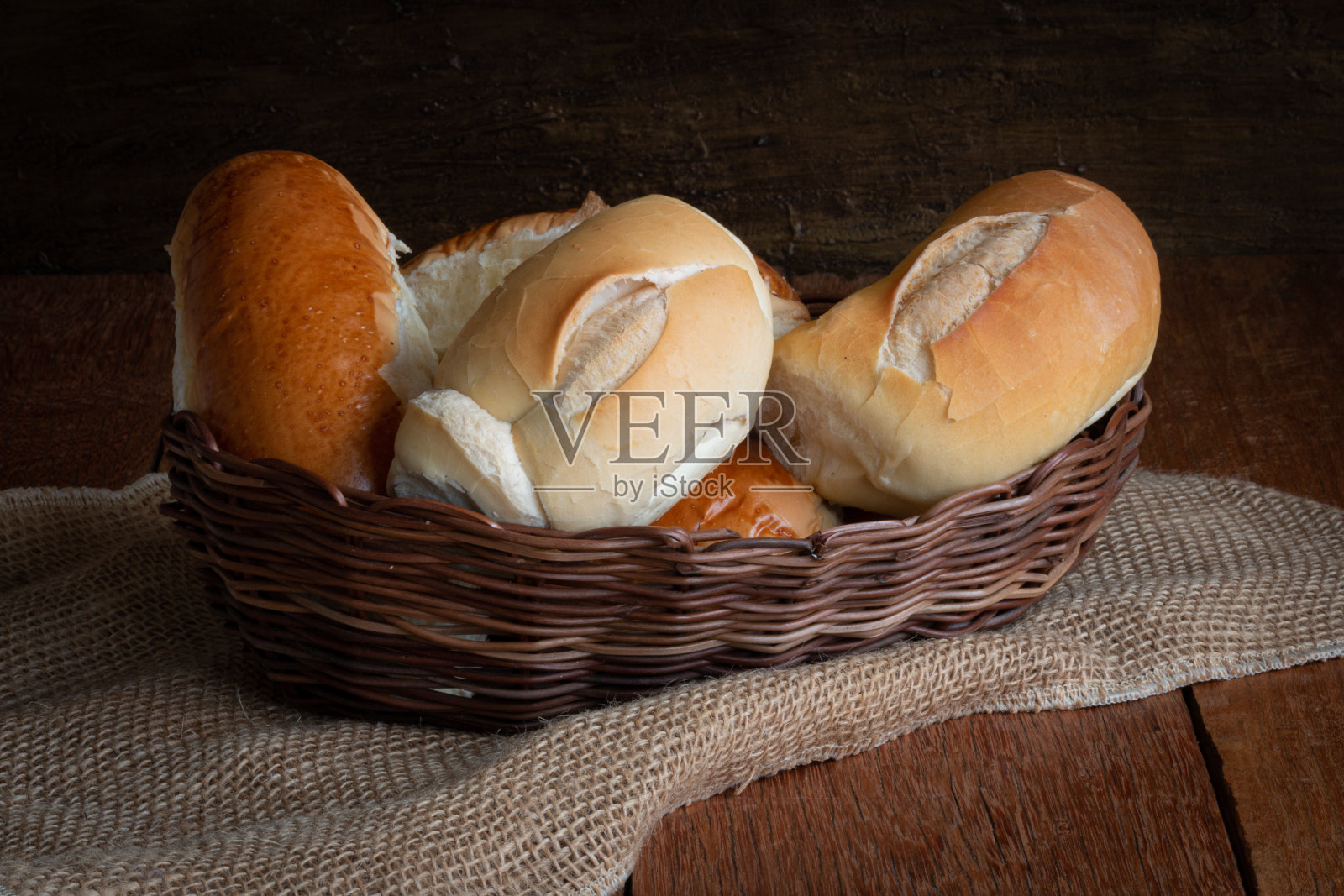 篮子里有面包，背景是质朴的木头。照片摄影图片
