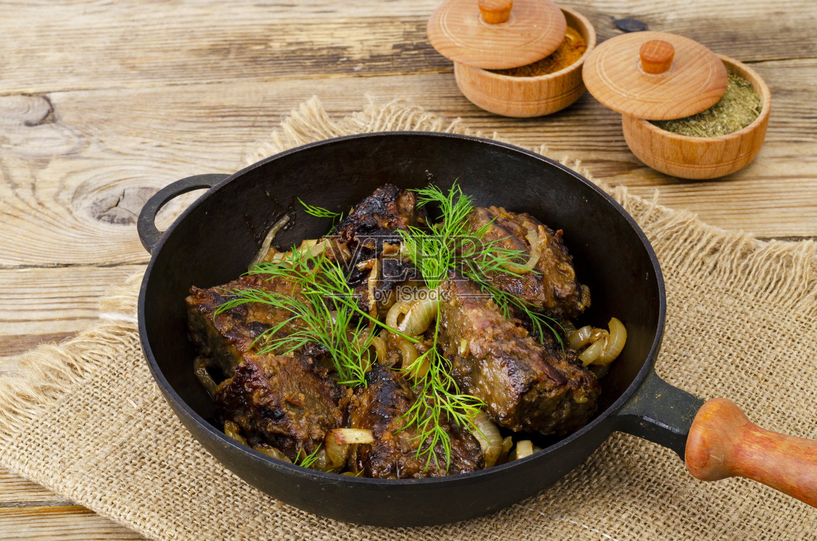 木桌上的铸铁煎锅，煎肝。照片摄影图片