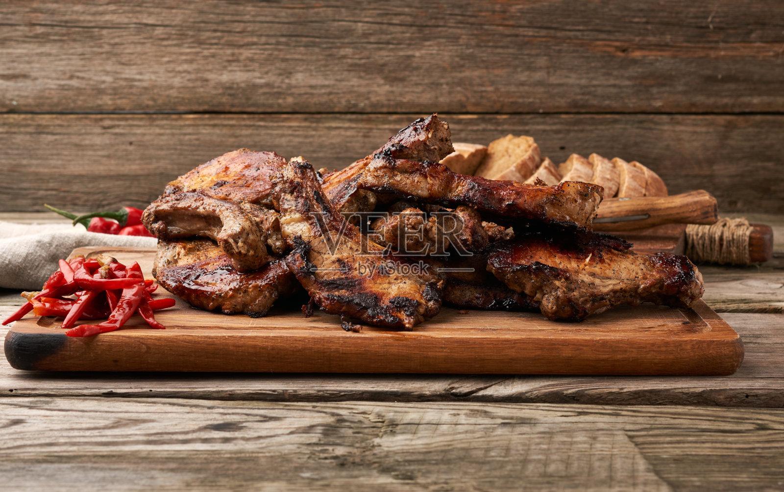 厨房砧板上的带骨烤猪肉和红辣椒照片摄影图片