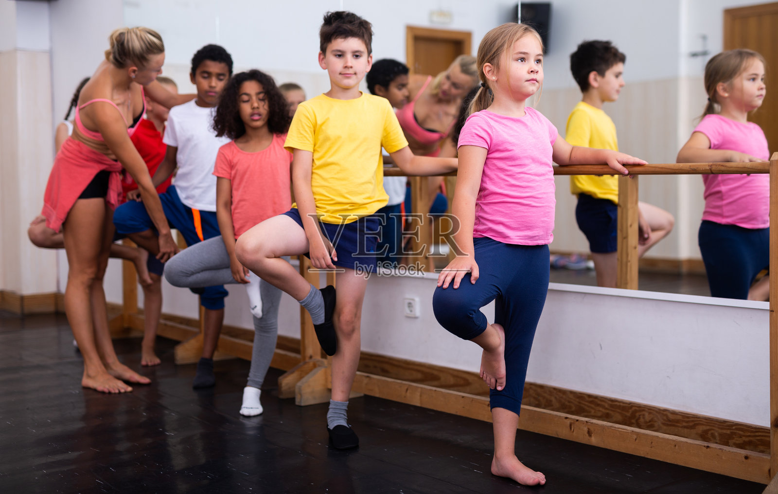 男孩和女孩沿着芭蕾舞棒训练照片摄影图片