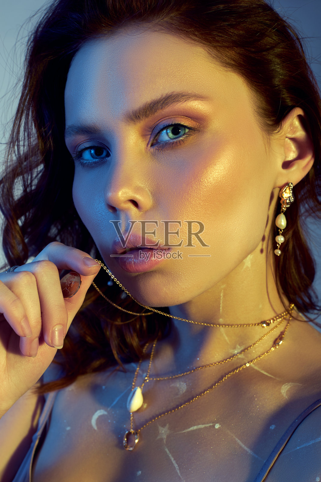 一个美丽的女人肖像与美丽的化妆，耳环和项链上的女孩。在女人胸前画十二宫星座照片摄影图片