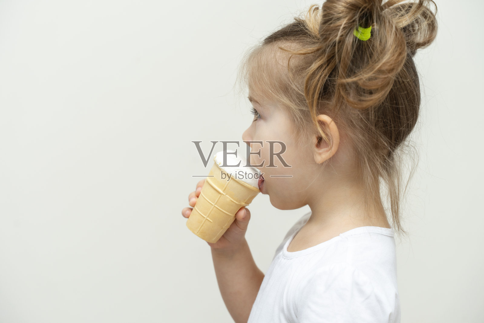 3-4岁的女孩穿着白色t恤吃冰淇淋。配置文件视图和复制空间照片摄影图片