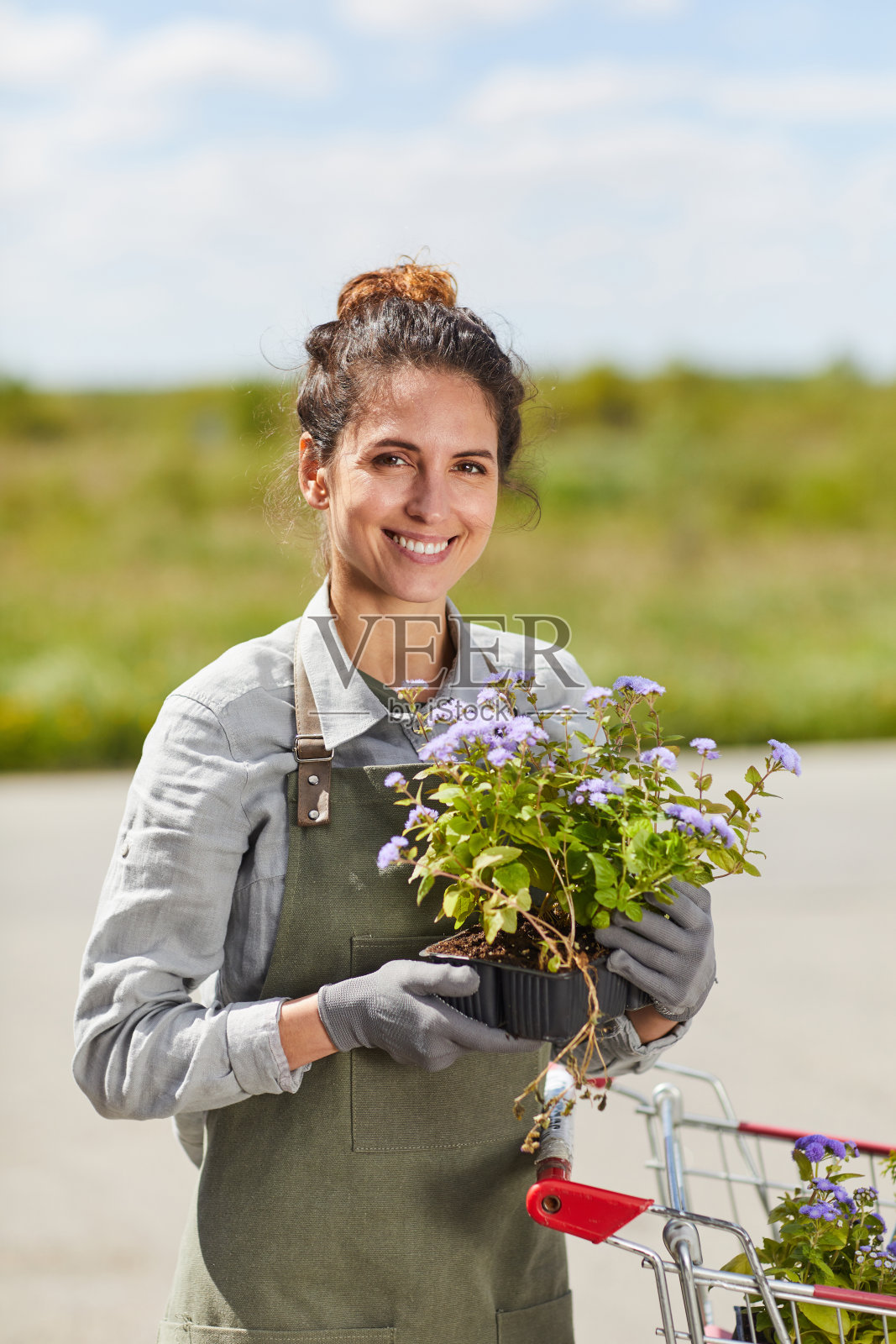 微笑的年轻女子在花园里拿着花照片摄影图片