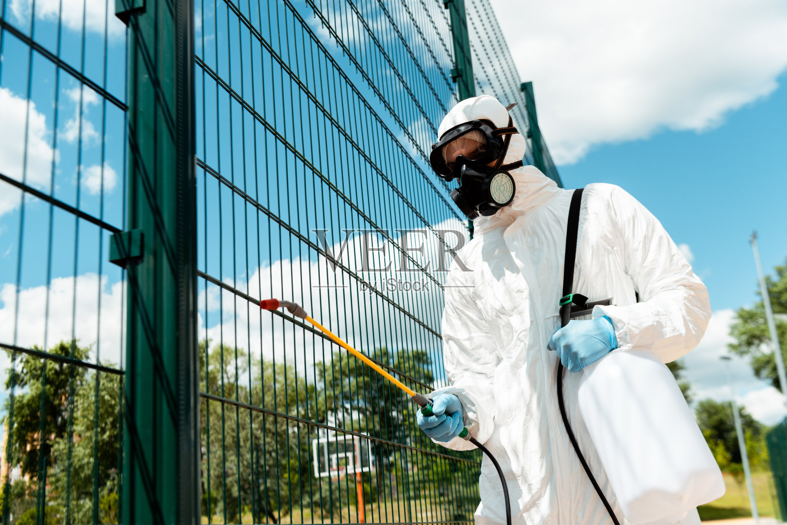 COVID-19大流行期间，负责公园篮球场防护服和防毒口罩消毒围栏的男性专家照片摄影图片