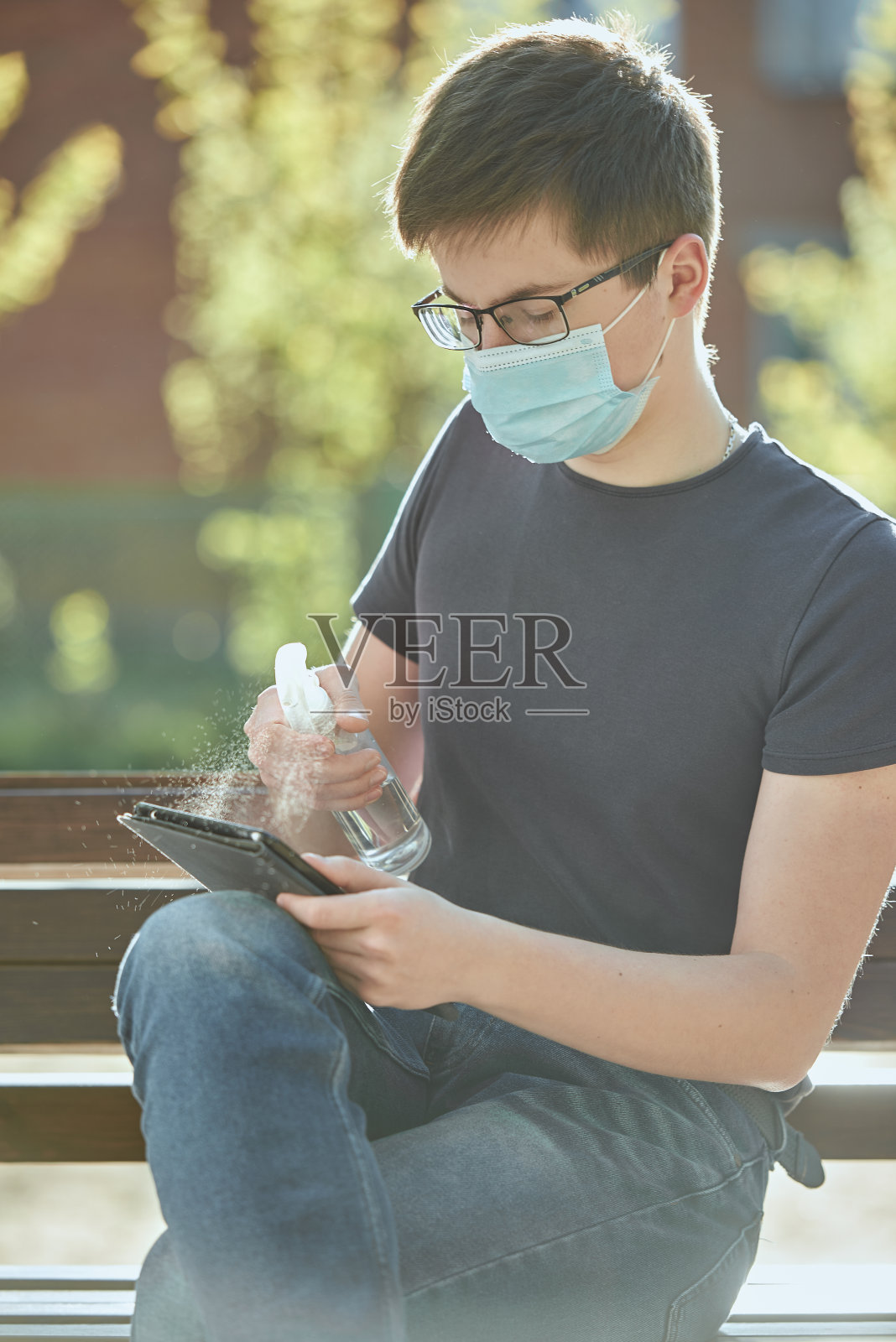 一个戴眼镜戴医用口罩用消毒液处理过的药片的人。照片摄影图片